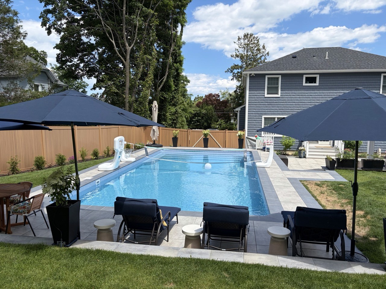 Rectangular in-ground pool with loungers and umbrellas by CMC Masonry