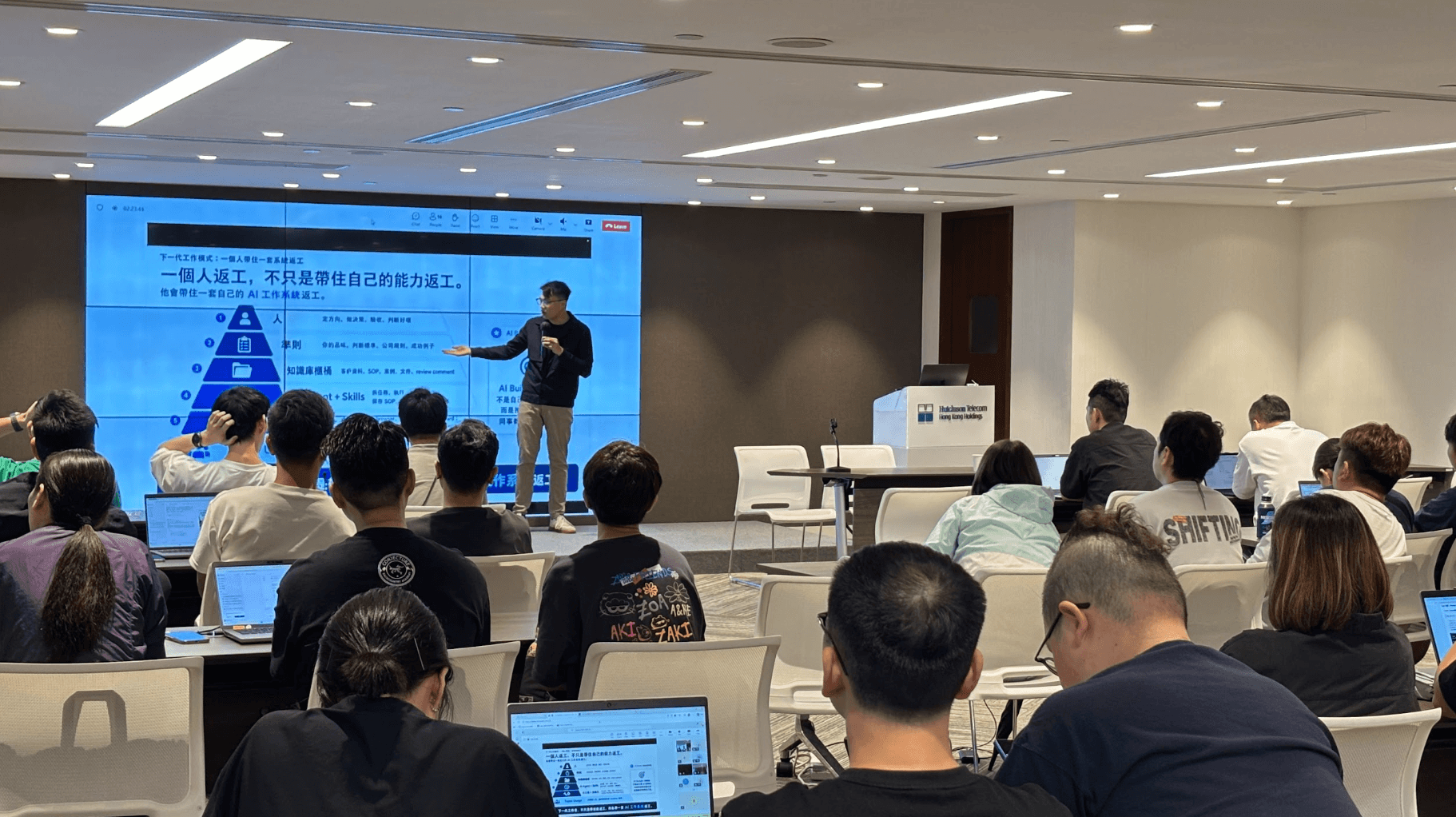 DotAI 導師在大屏幕前講解市場推廣方案與 AI startup demo workflow。