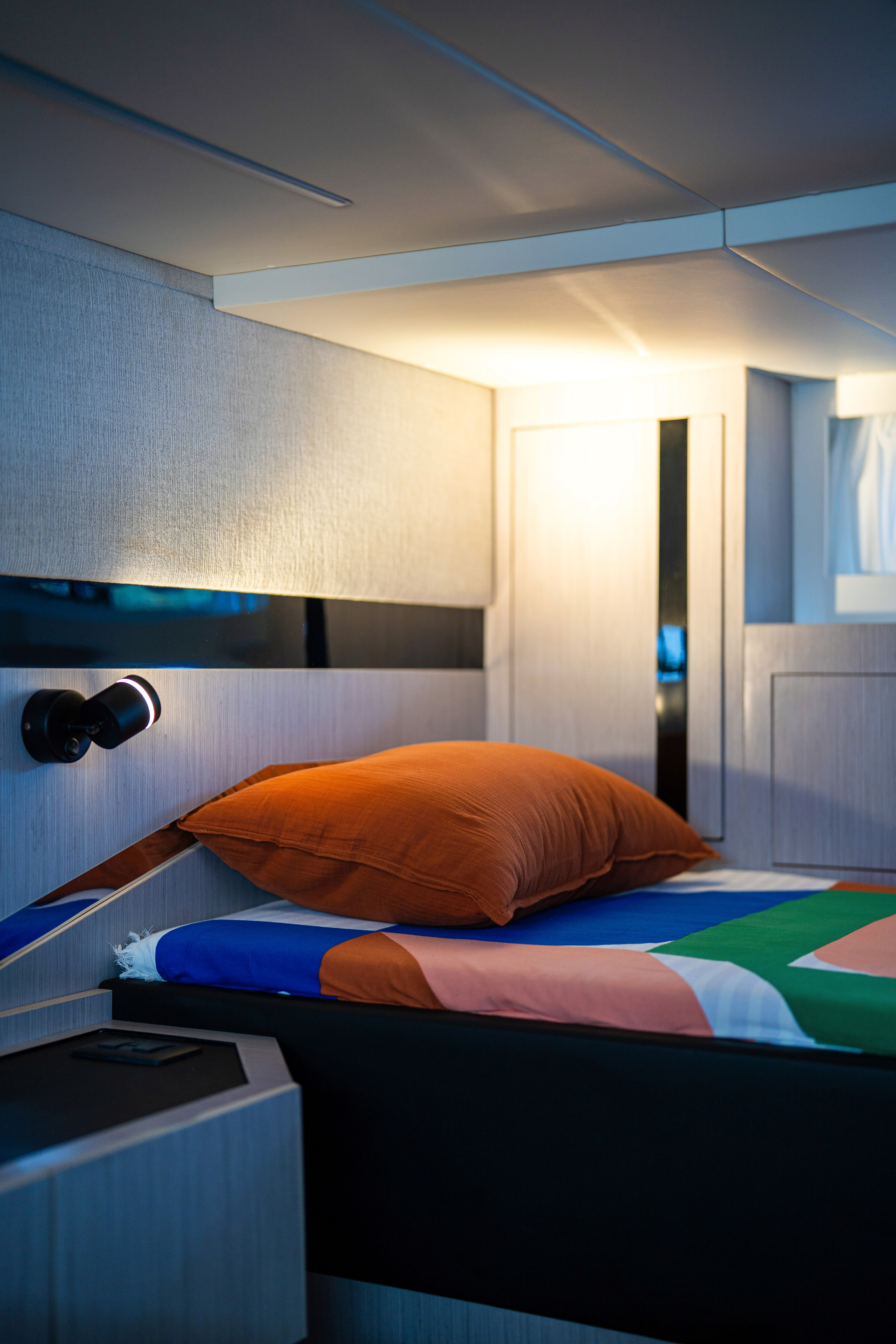 Une salle de bain moderne et compacte comprend des toilettes blanches élégantes, un comptoir noir avec un lavabo et une serviette orange vif suspendue à côté.