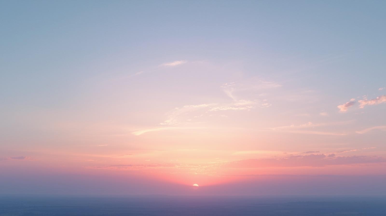 Soft dawn sky with glowing clouds reflecting warm morning sunlight
