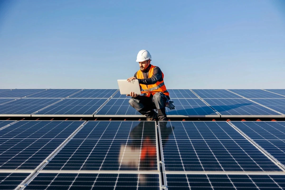 Technician with laptop on solar panels.