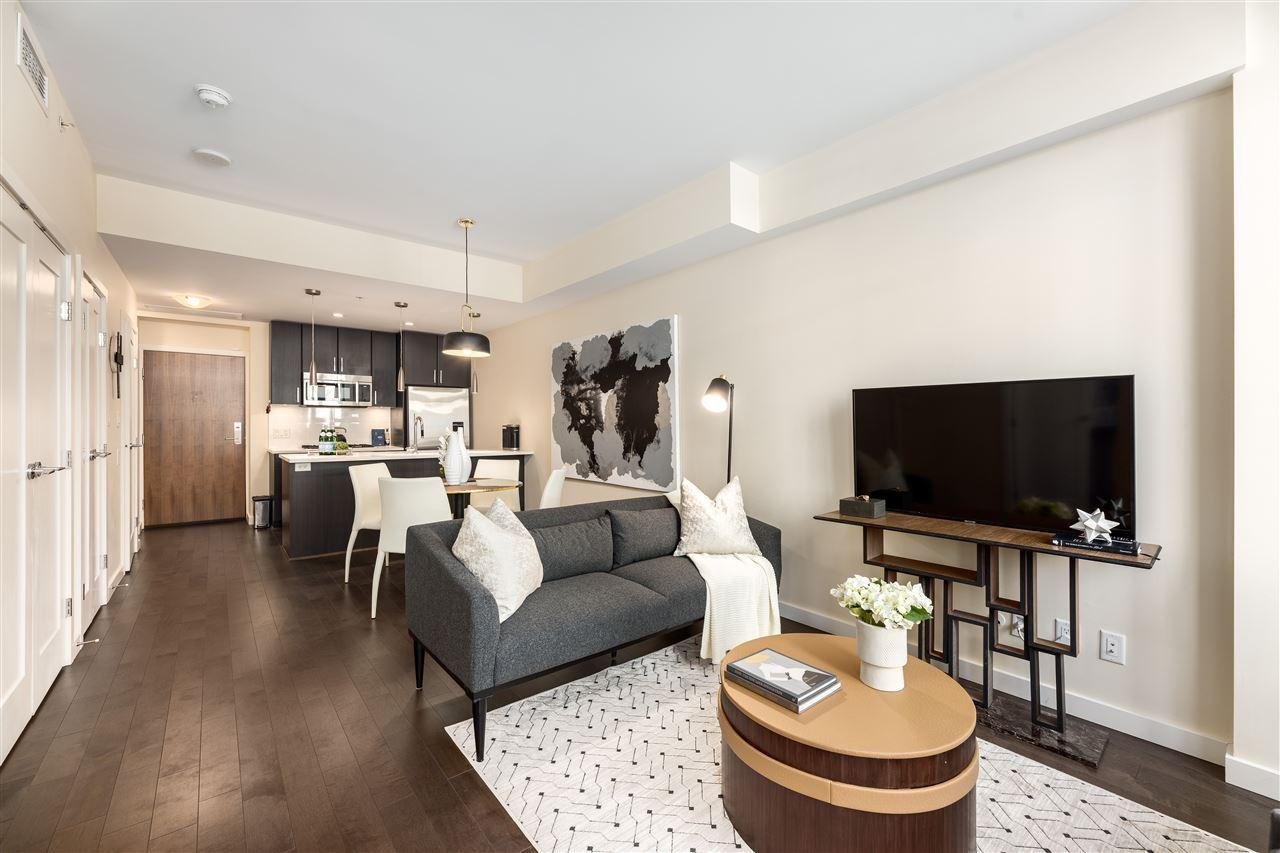 Modern living room with a gray sofa, wooden coffee table, and a TV against a light wall, creating a cozy atmosphere.