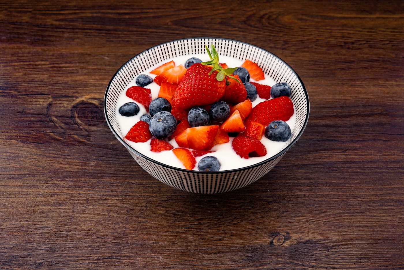 A bowl of yogurt topped with fresh strawberries and blueberries as a protein-rich snack