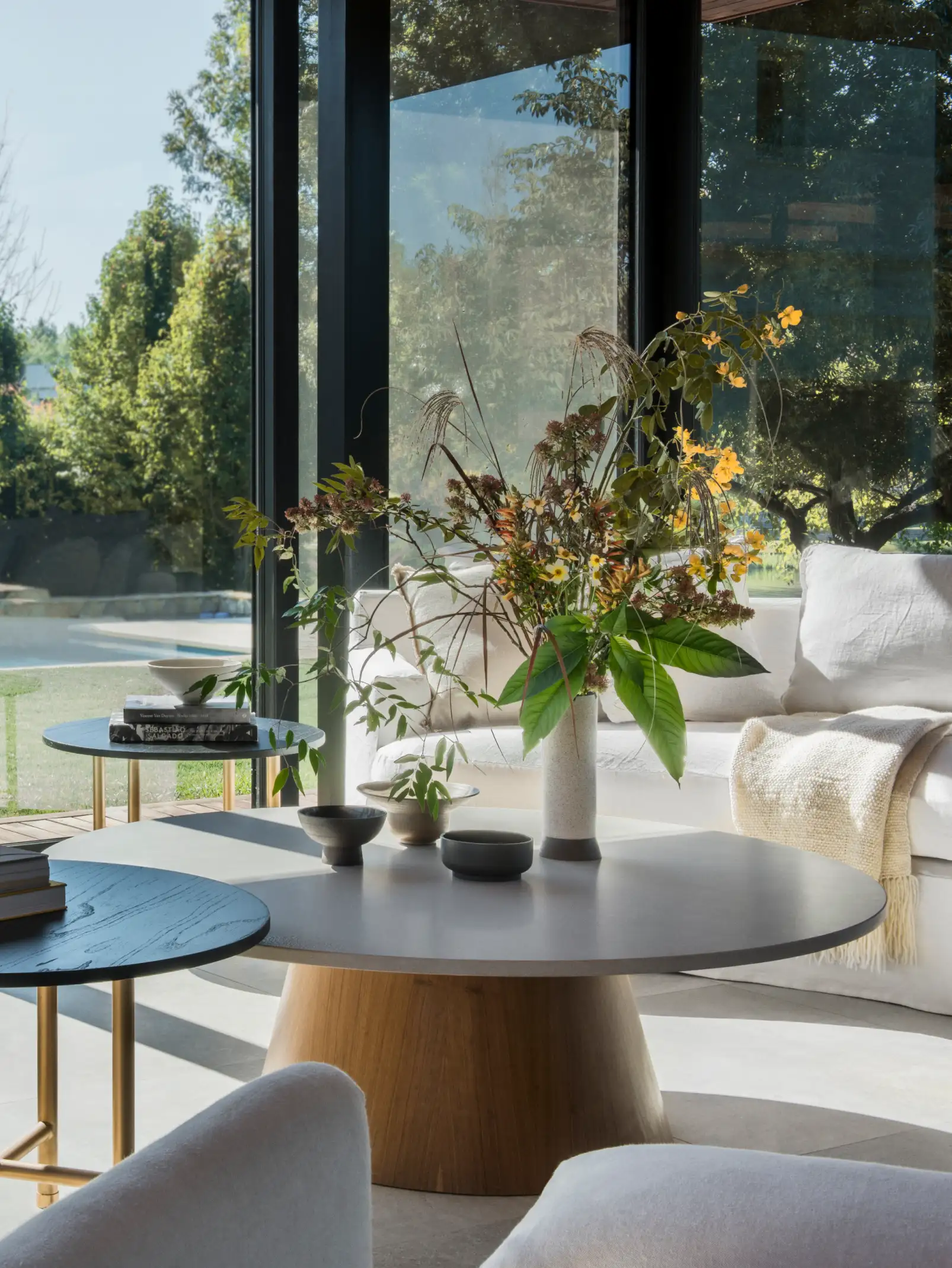 Sala luminosa con arreglo floral natural sobre mesa redonda para estudios de interiorismo que destacan armonía entre exterior e interior.