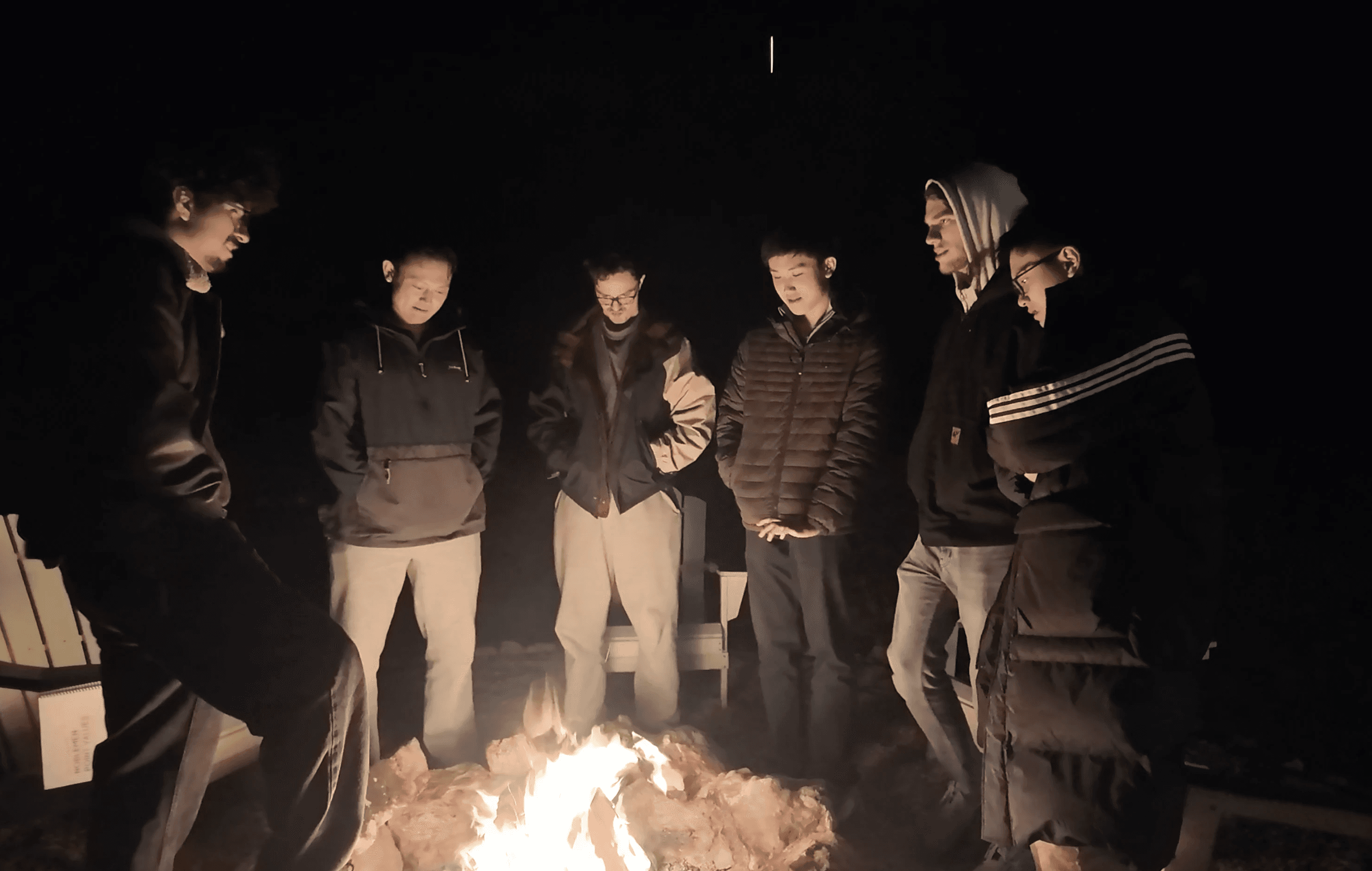 Guys hanging out around campfire