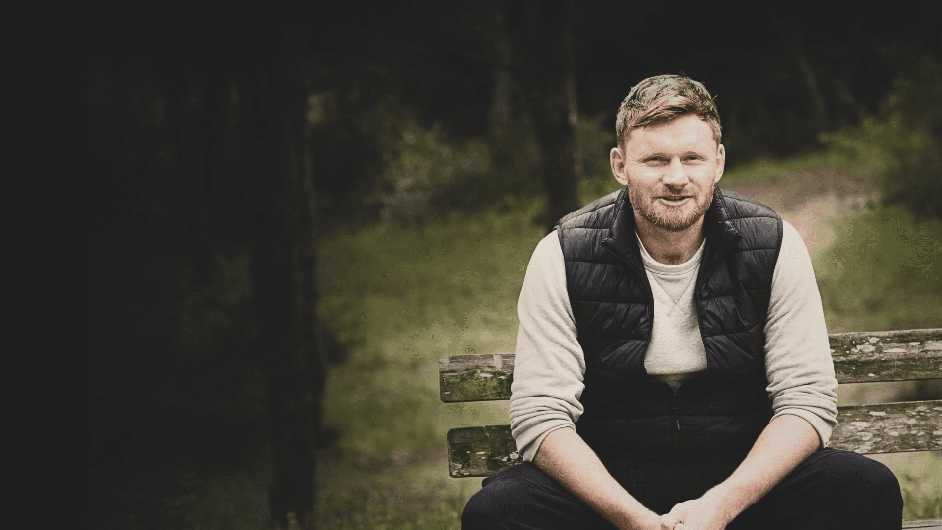 Tom sitting on a park bench reading a newspaper