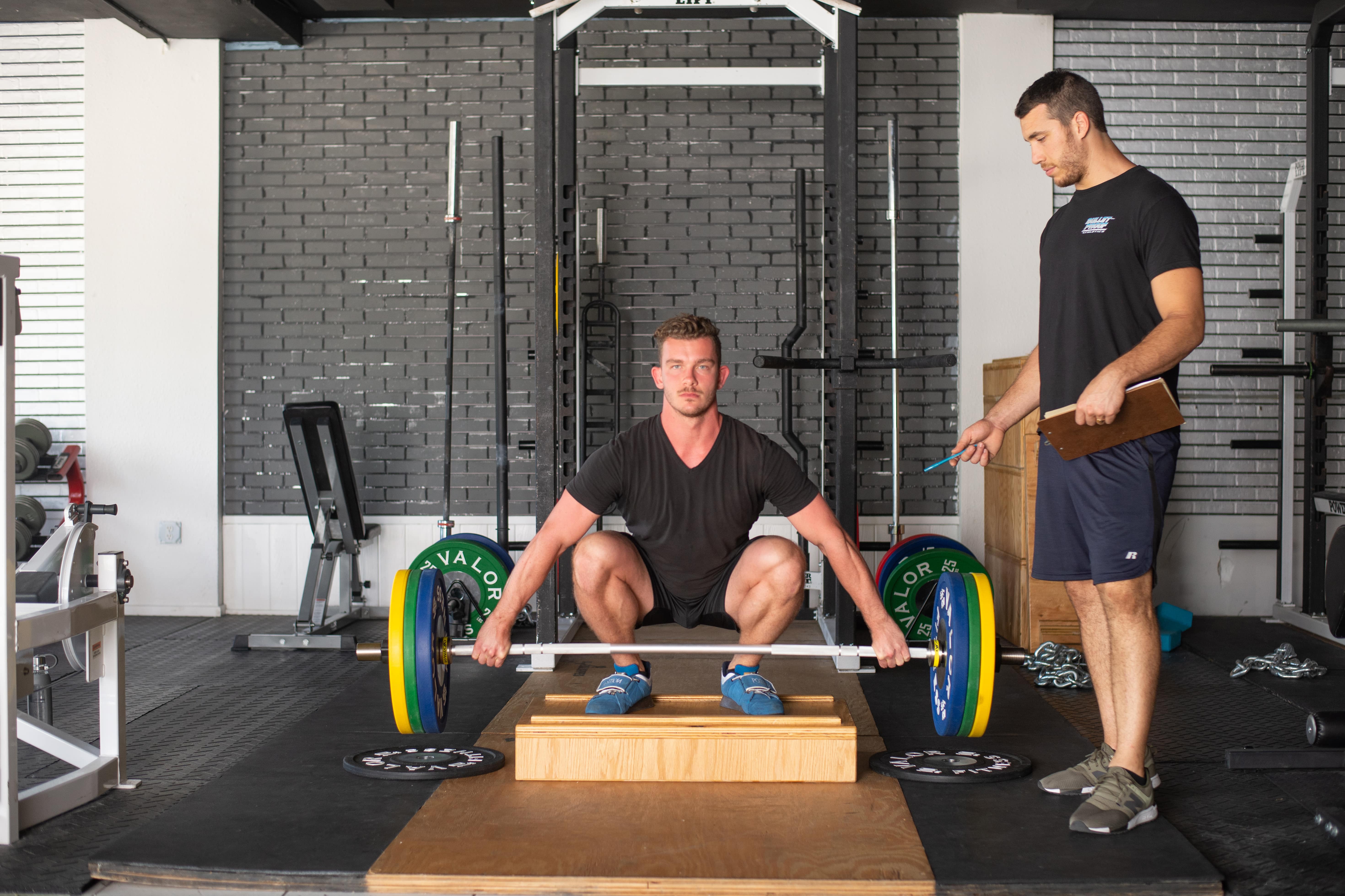 Smiling young woman sitting on exercise ball using cellphone