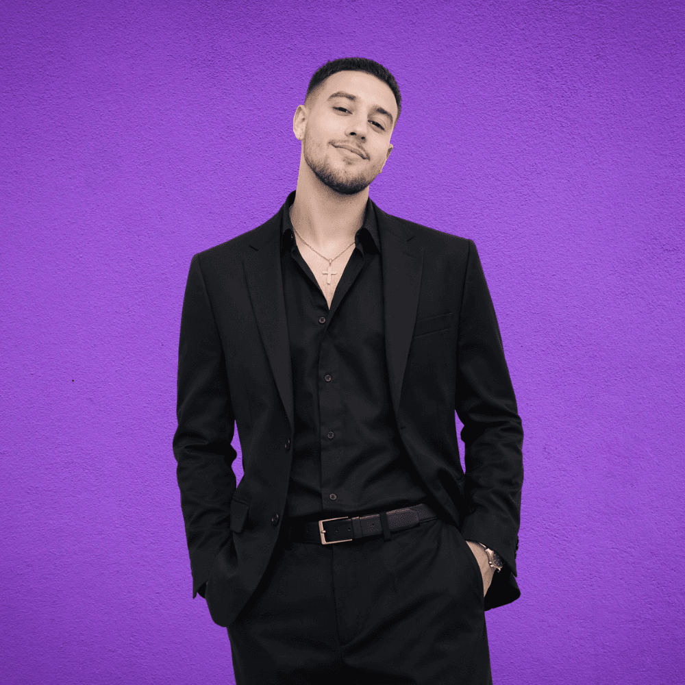 a man standing with his hands in his pockets in front of a large field