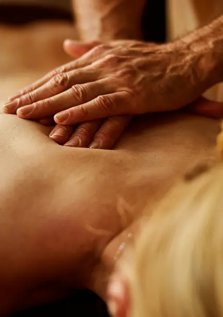 A massage therapist's hands gently applying pressure on a relaxed person's bare back, creating a soothing and calming atmosphere, ideal for stress relief and wellness.
