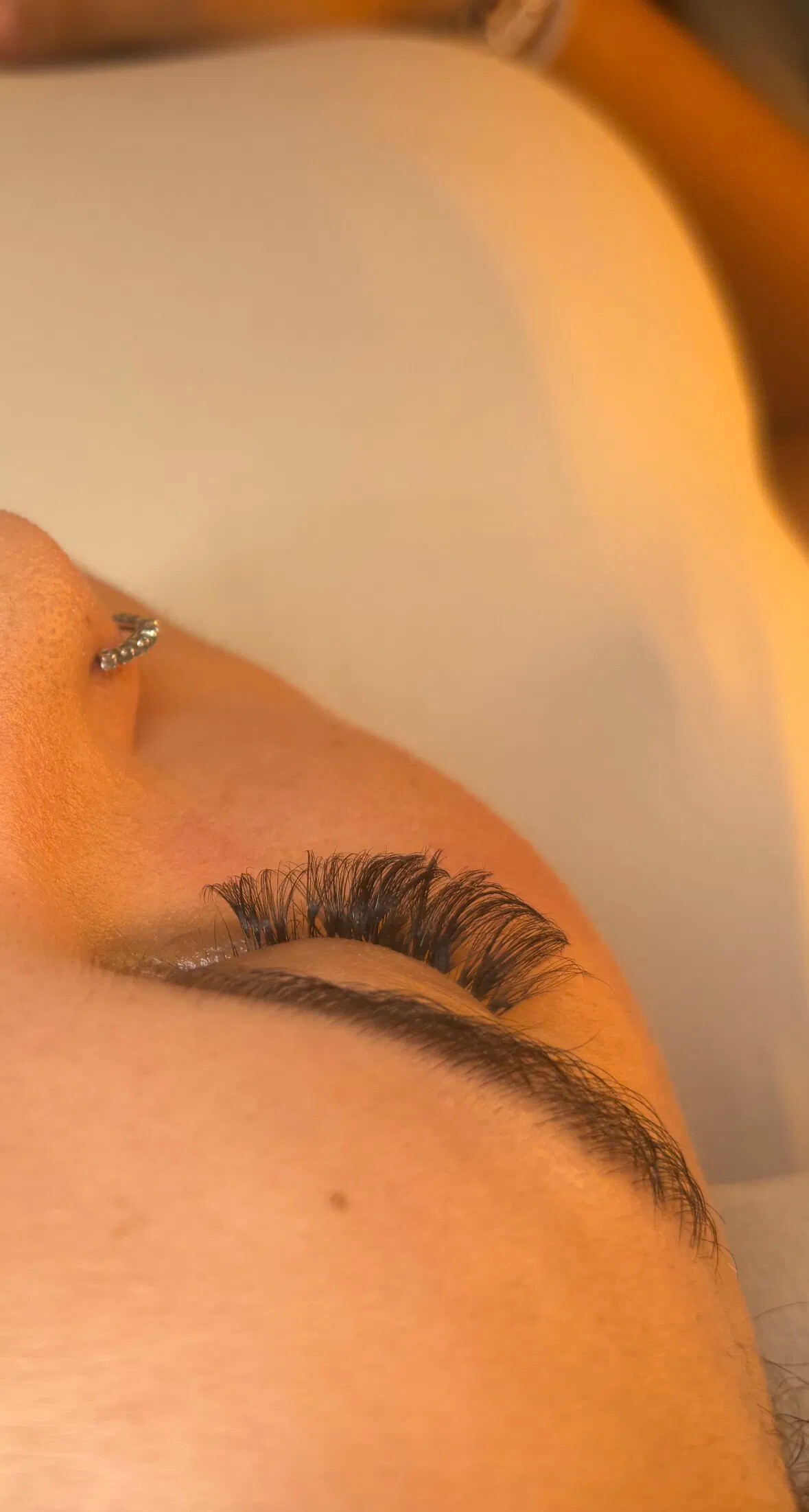 Pose d’extensions de cils sur cliente allongée – résultat volumineux et soigné, travail précis d’une technicienne experte en beauté du regard.