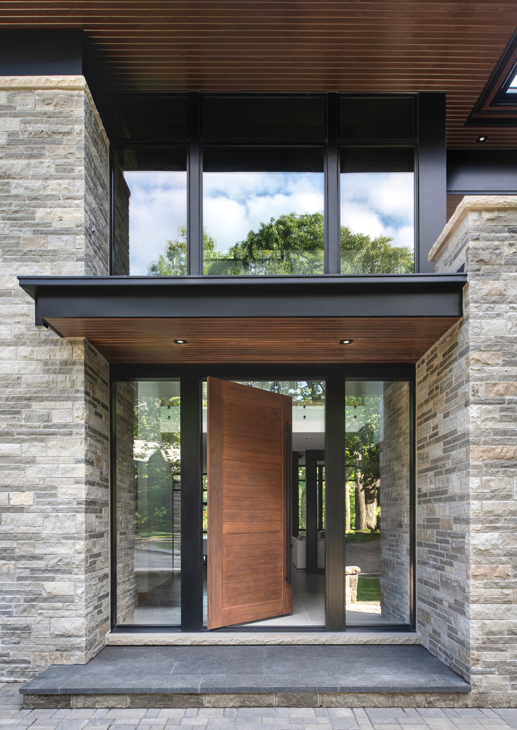Sunlit modern interior hallway featuring floor-to-ceiling windows and a dining area.