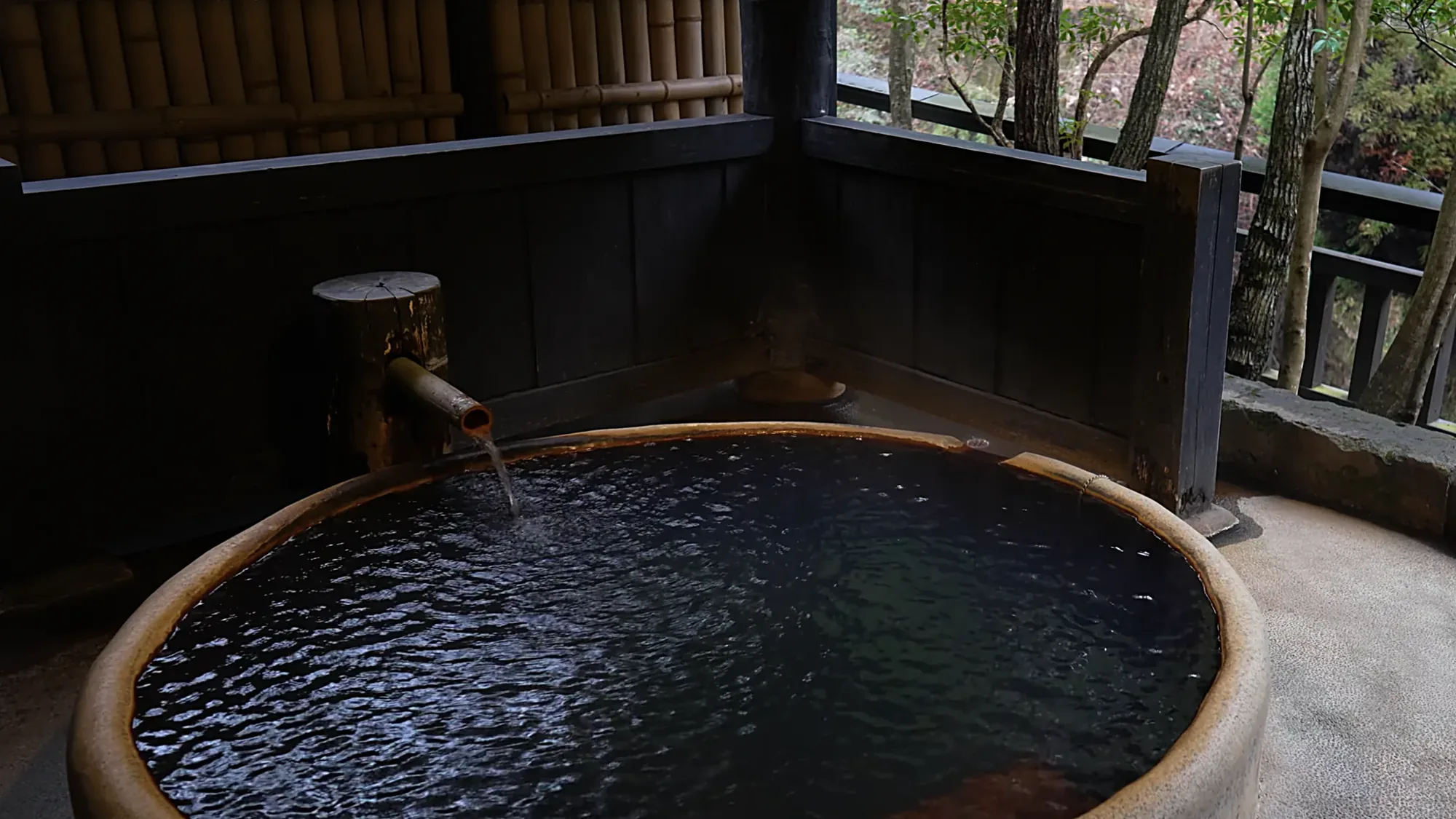 A round timber tub with its bamboo spout running, the valley beyond the rail