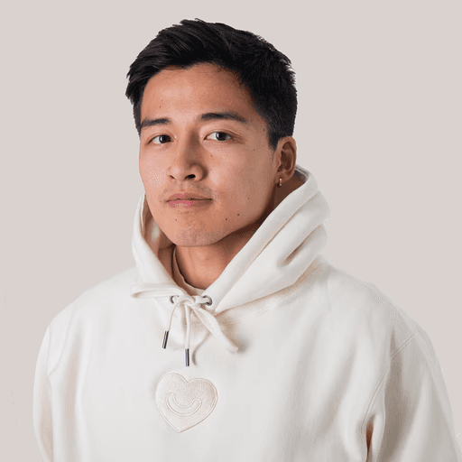 Man in denim jacket smiling outdoors.