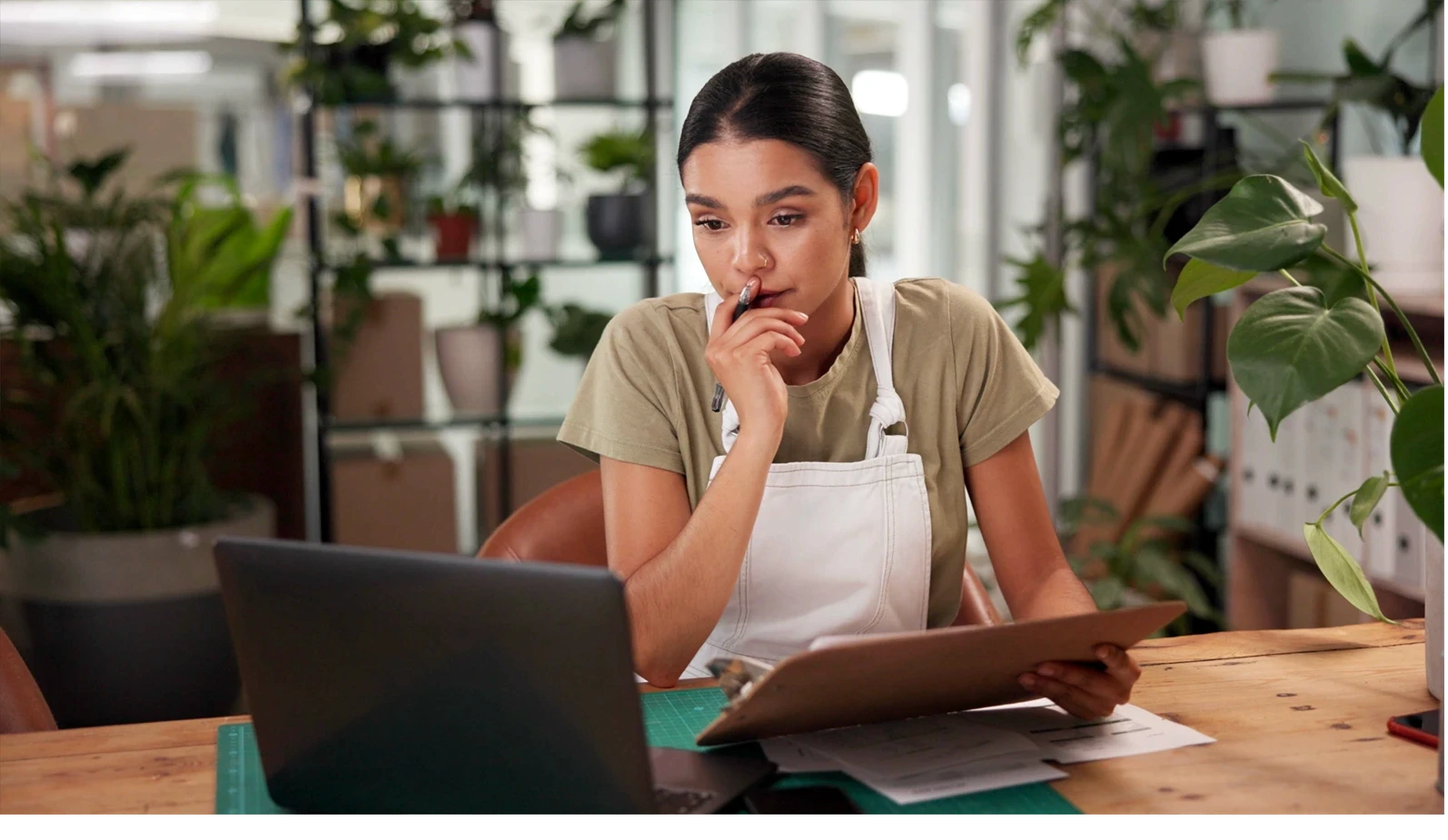 Woman, florist and clipboard with laptop at shop with stress, thinking and problem solving at small business. Person, pc and sustainability for plants with mistake, crisis and lost order on web store