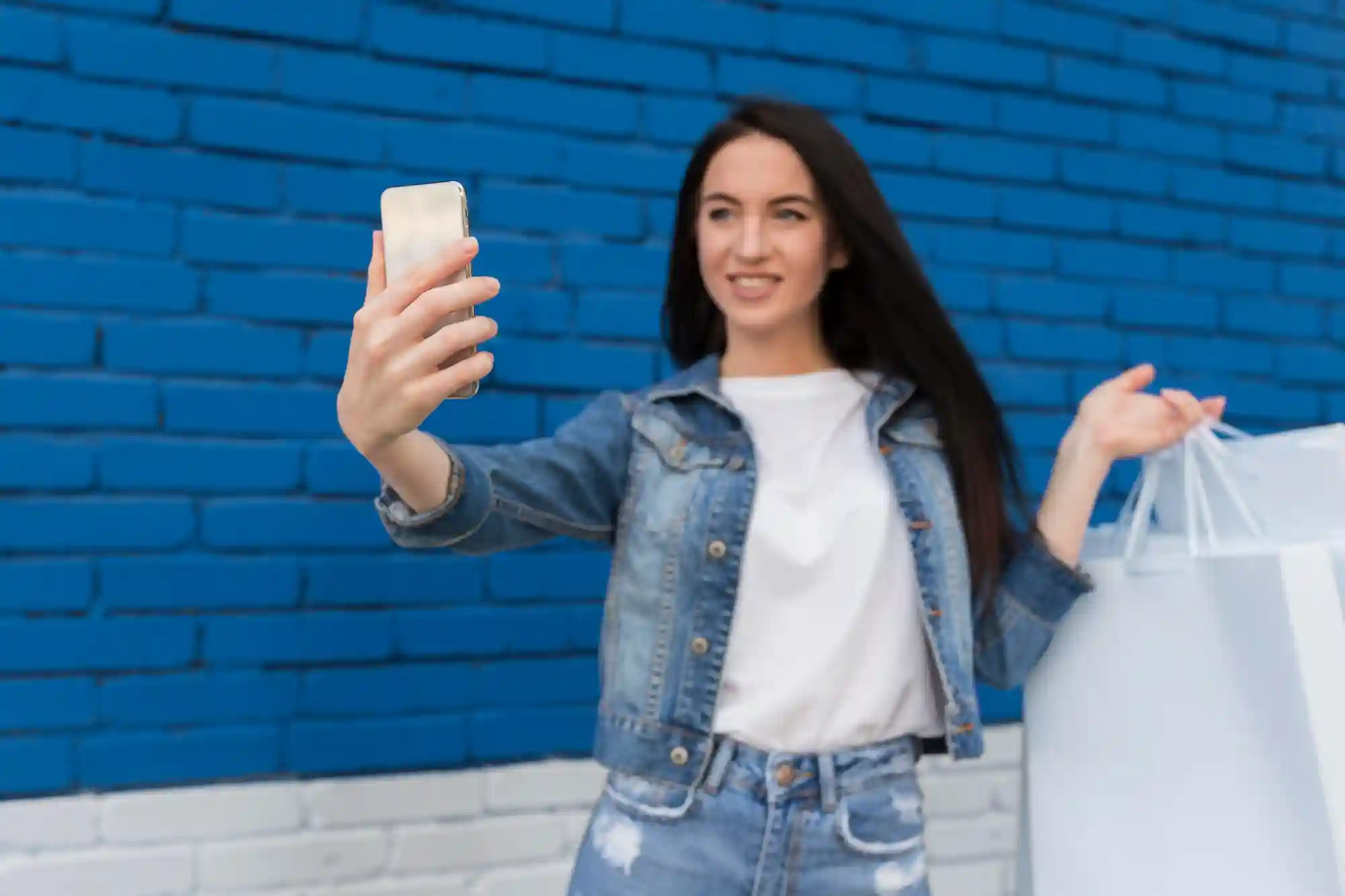 A woman taking a selfie while holding shopping bags, illustrating the social and retail side of cinema outings.