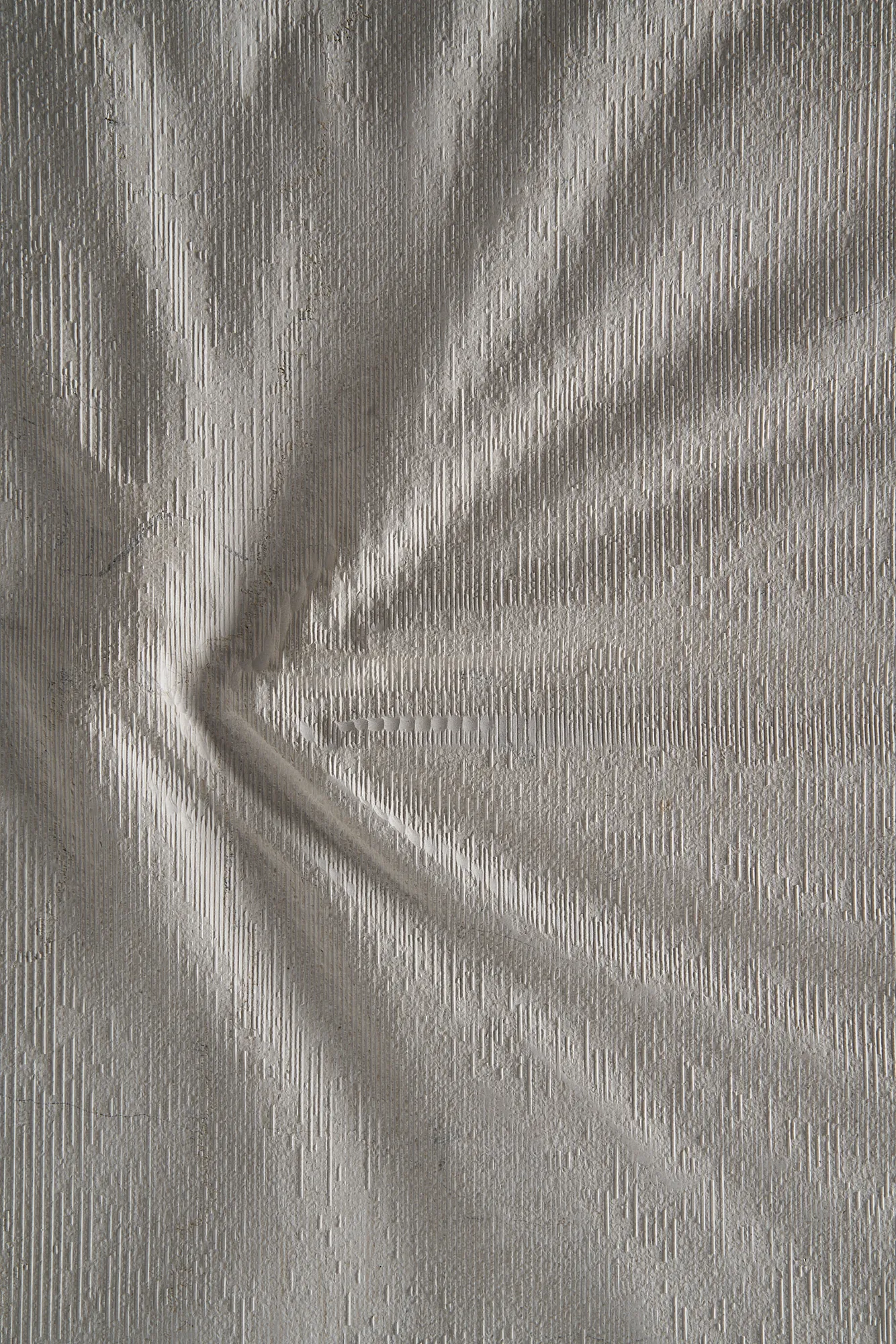 Detailed view of a Curtis natural stone panel with radiating fabric-like creases and textured carved lines.