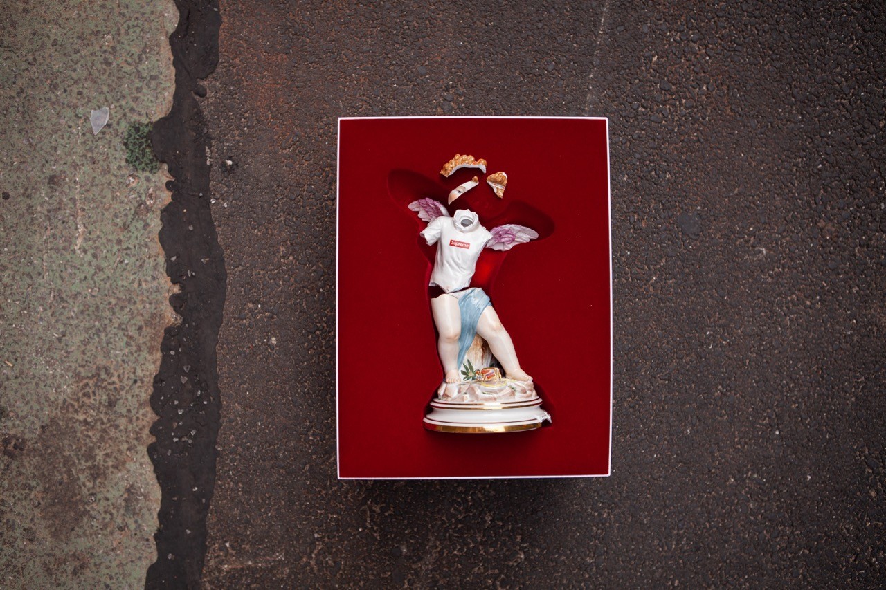 Meissen figurine posed on a red square background, photographed on asphalt.
