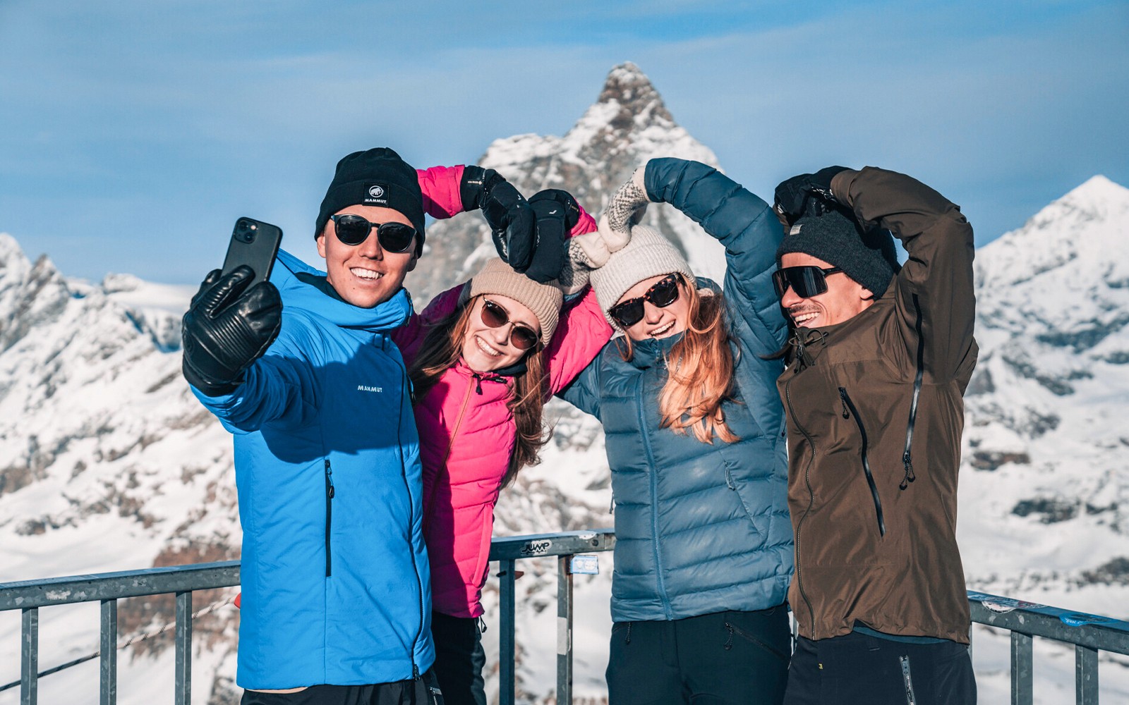 बर्फीले पहाड़ों के दर्शनीय मंच पर समूह सेल्फी ले रहा है।