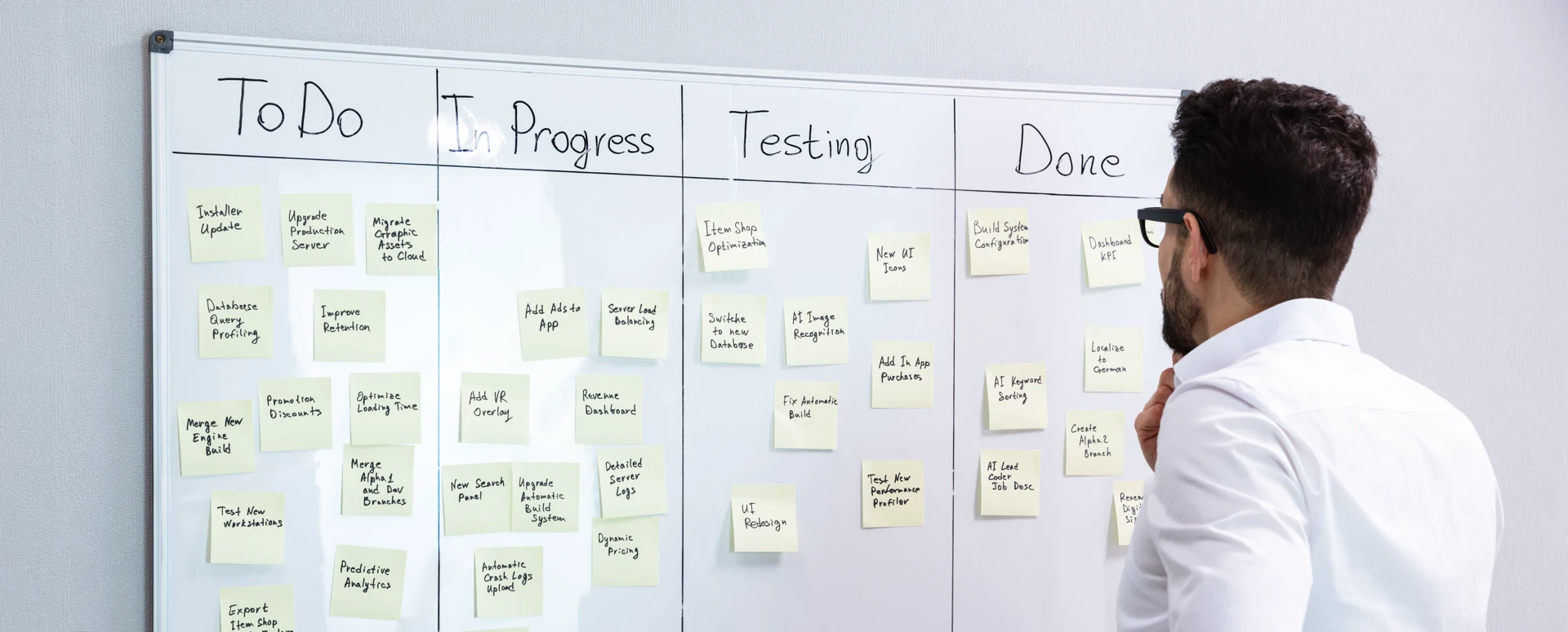 Kanban board in action: Developer reviewing Agile project workflow with To Do, In Progress, Testing, and Done columns. Sticky notes show software development tasks, illustrating Kanban system for productivity optimization in tech teams