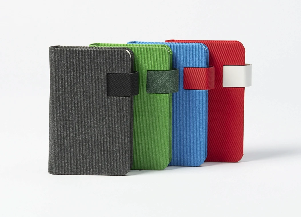 Textured fabric journal with strap closure in grey, green, blue, and red colors