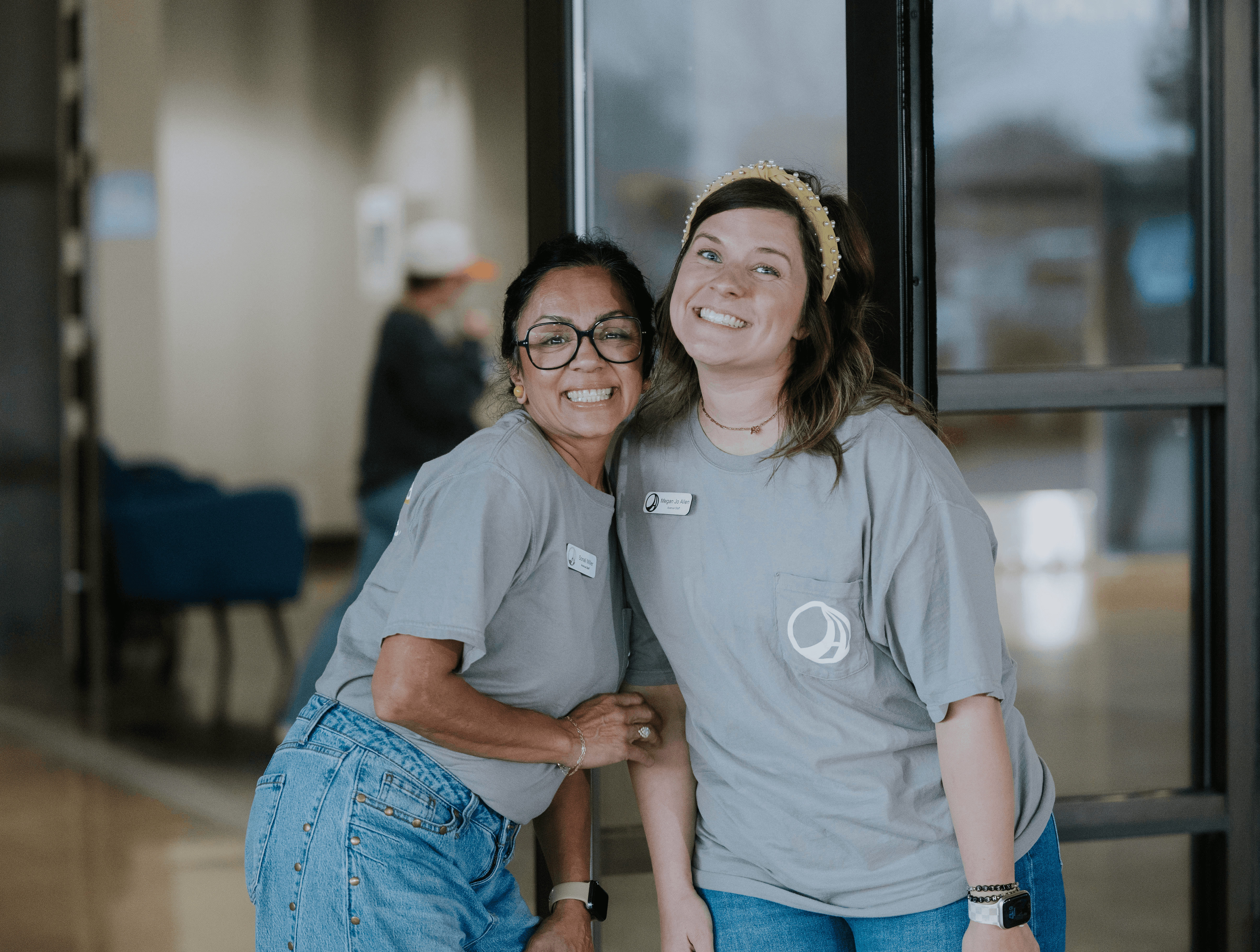 Three individuals stand together outdoors, smiling, with a modern building in the background.