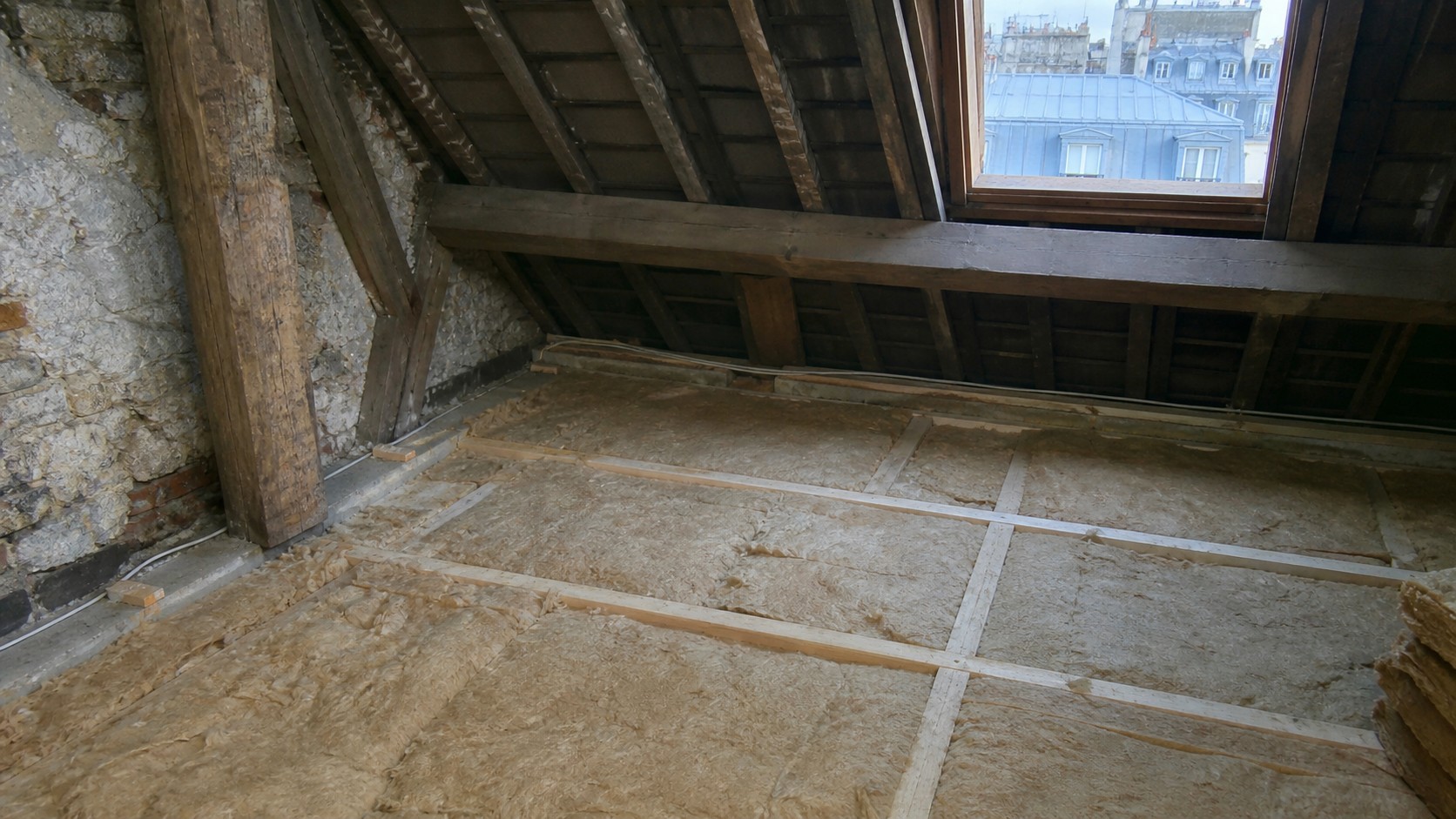 Combles isolés sous toiture à Paris avec laine minérale posée entre solives, illustrant l’impact de l’isolation des combles sur le DPE et la note énergétique d’un logement.
