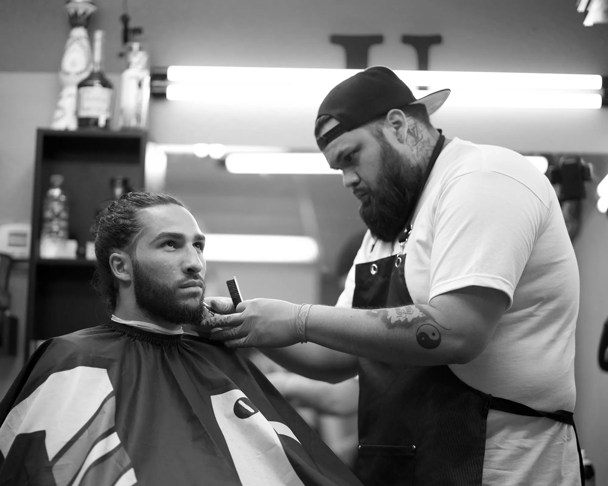 Barber in a striped cape getting a haircut