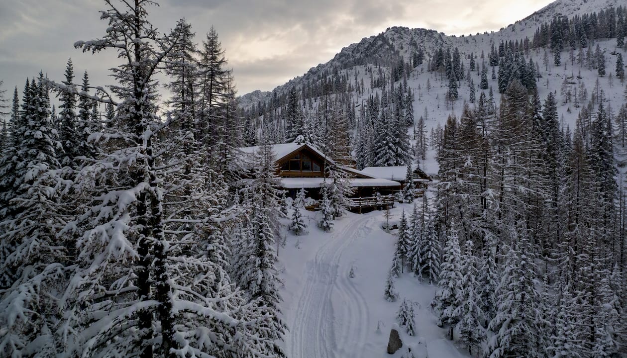Snow-covered lodge exterior beside a winter trail in the Altai