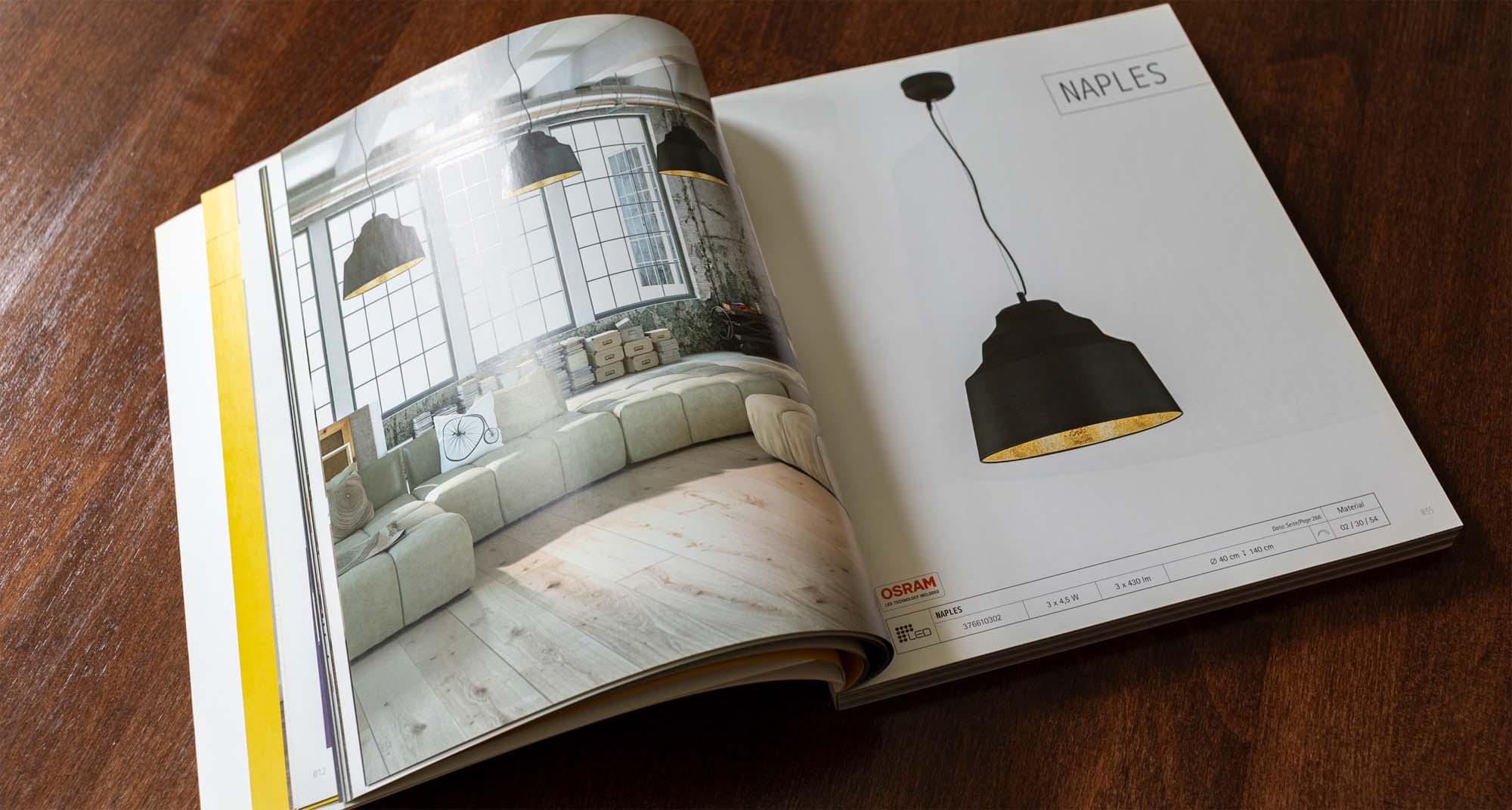 Print- und Editorial-Design für den TRIO Katalog: Aufgeschlagenes Produktmagazin mit einer Leuchten-Doppelseite auf einem Holztisch.