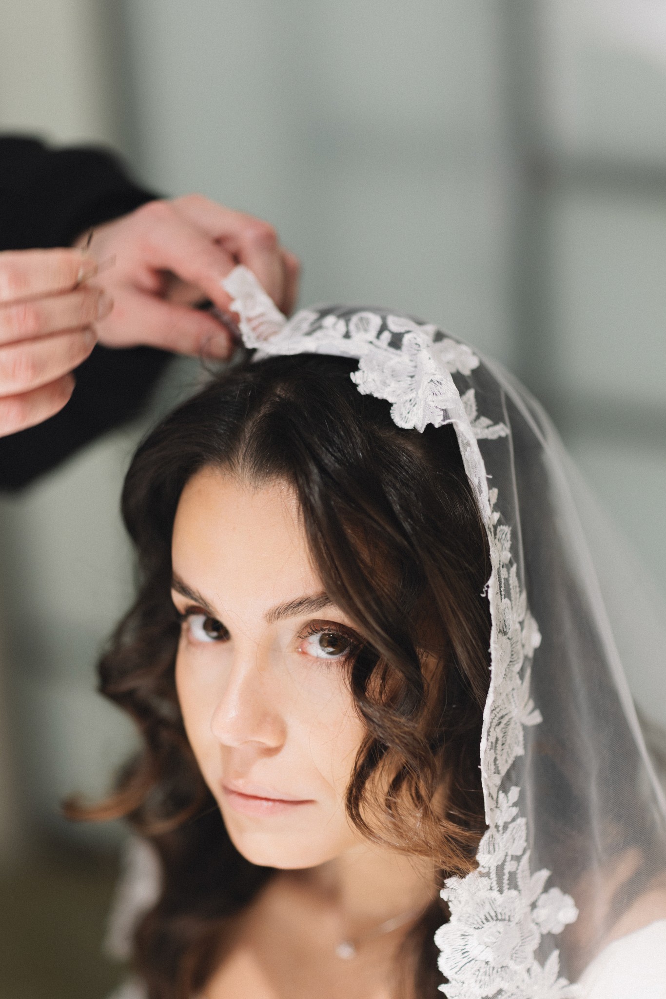 Sposa con velo di pizzo applicato da mani delicate, preparativi di matrimonio al Circolo di Lettura a Parma