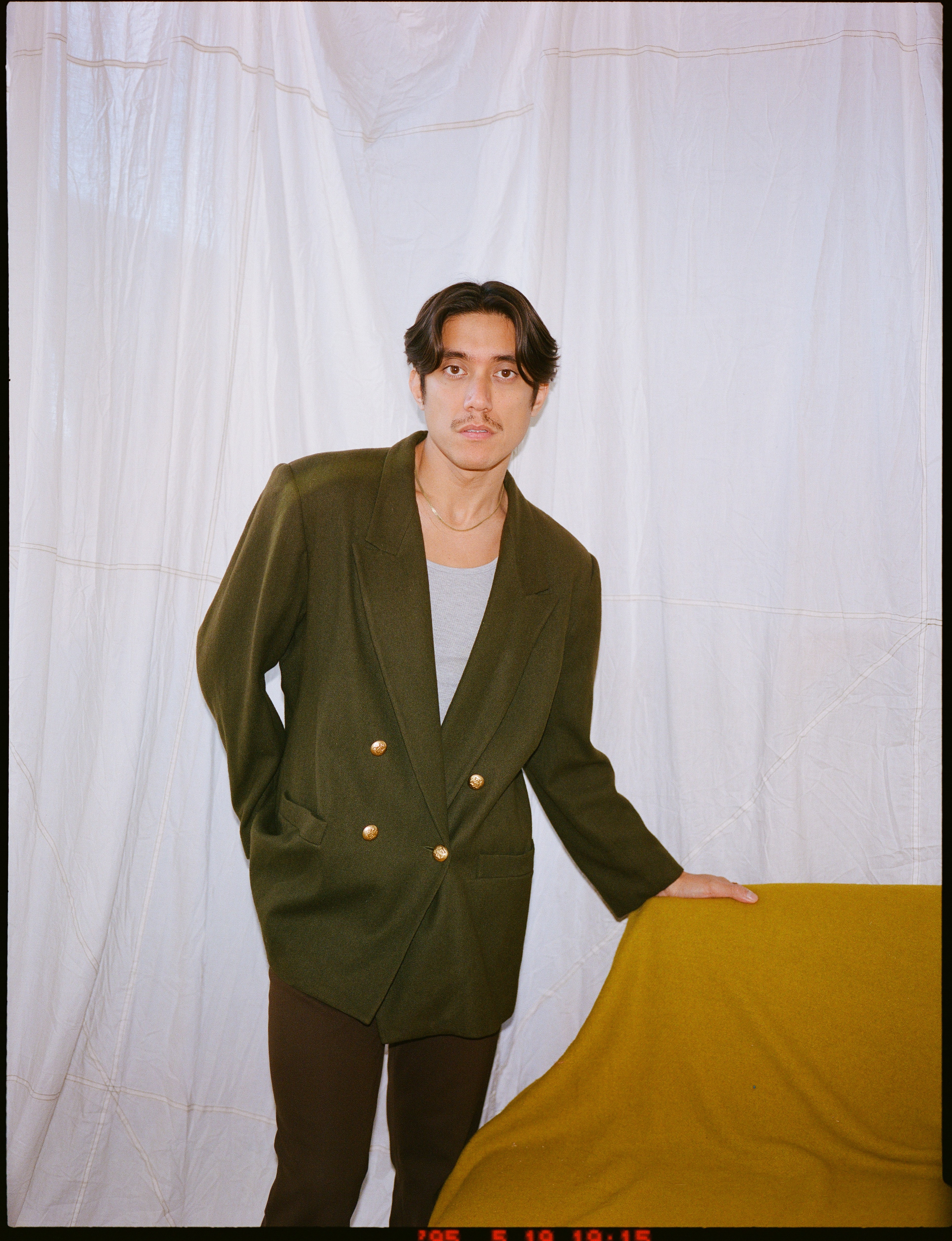 A tan sighthound stands in a grassy field.