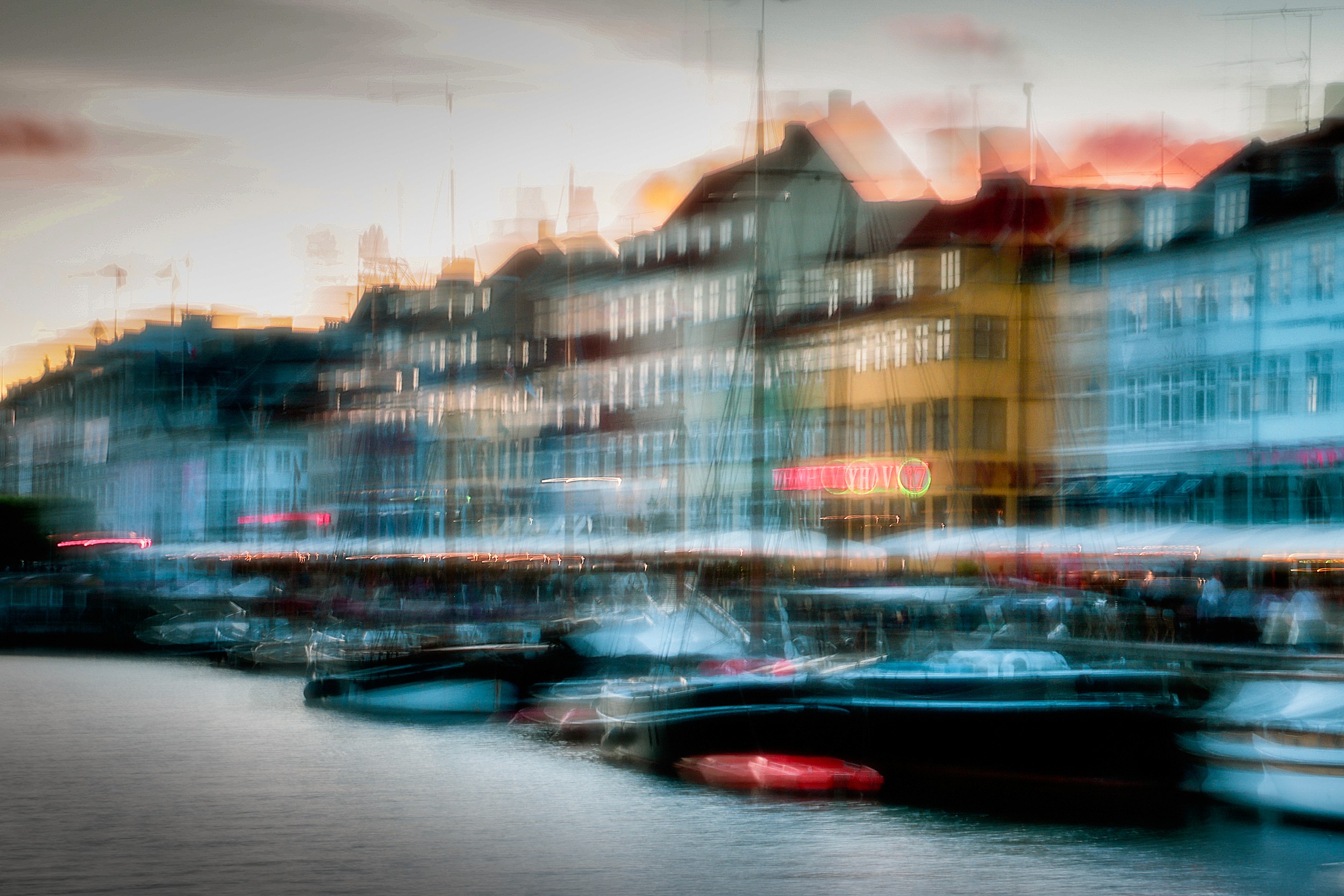 Blurry cityscape of Nyhavn harbor in Copenhagen, vibrant lights and boats smeared by motion