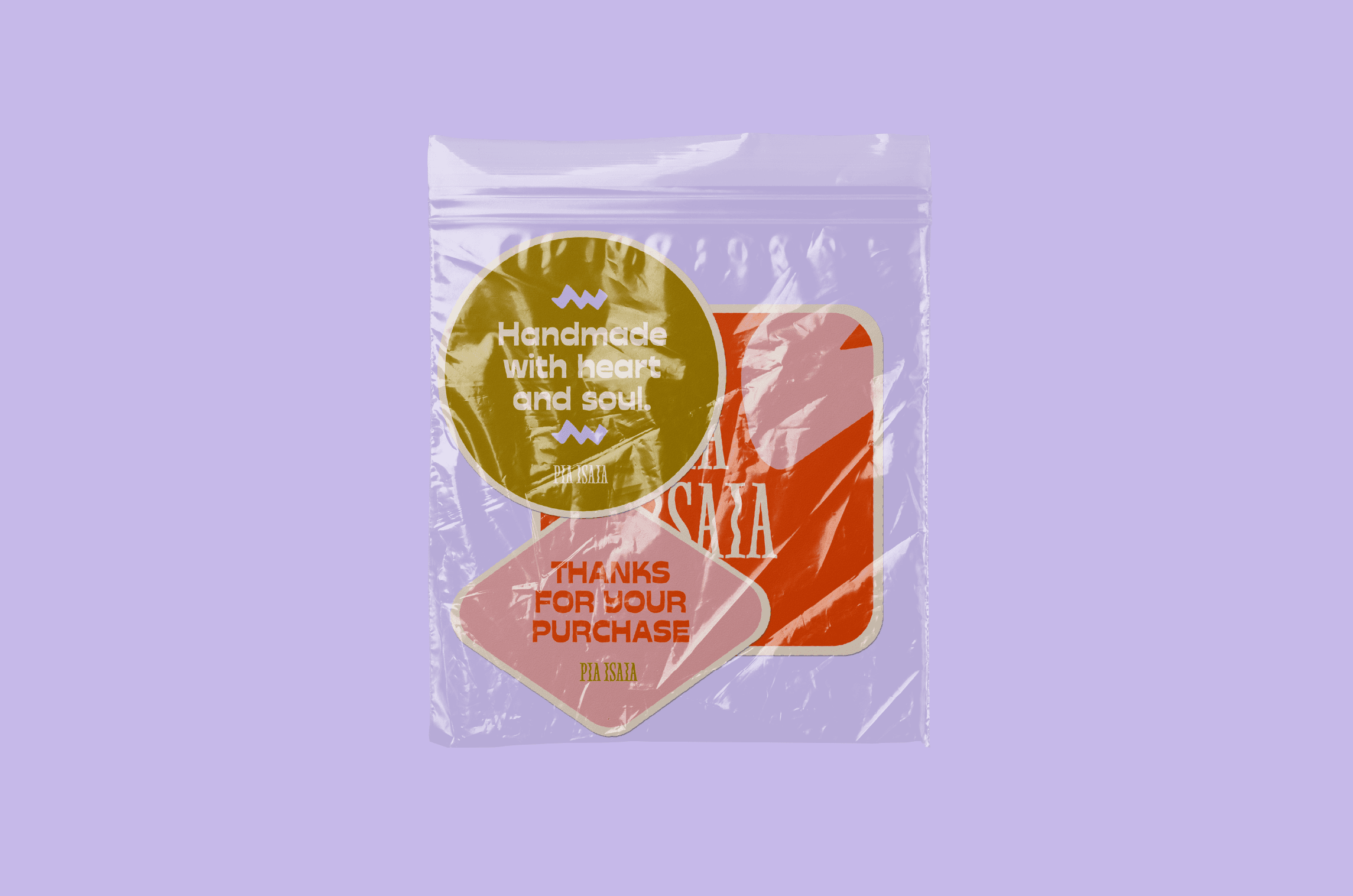 A clear plastic bag on a purple background contains a gold sticker with the text "Handmade with heart and soul," sitting above a red square with "Thanks for your purchase" printed in white, suggesting an aesthetic presentation for handmade artisanal product packaging.