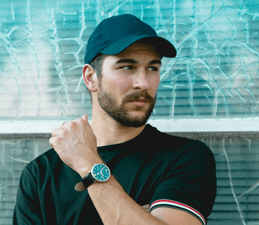 man wearing black crew-neck shirt and black cap in front of glass wall
