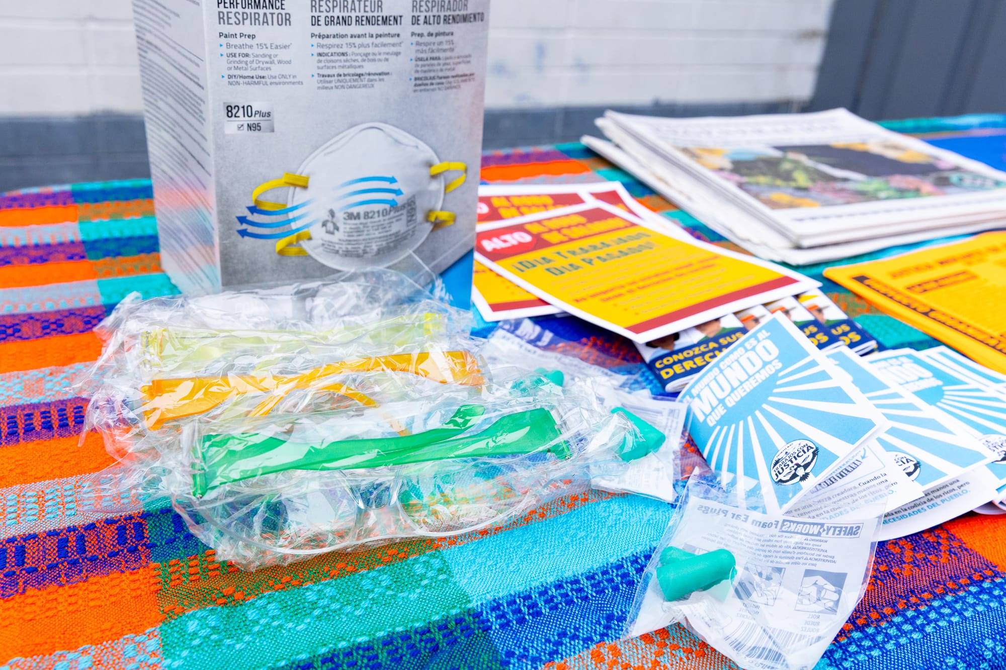 earplugs, masks, and Spanish language pamphlets on a table with a colorful tablecloth