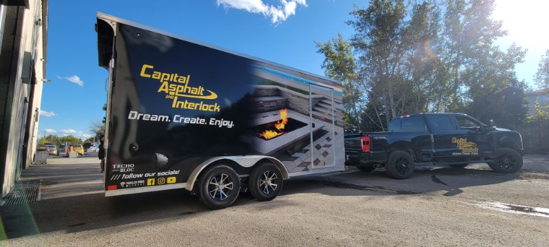 Commercial trailer wrap for Capital Asphalt and Interlock being towed by a branded pickup truck, showcasing fleet vehicle graphics and mobile advertising.