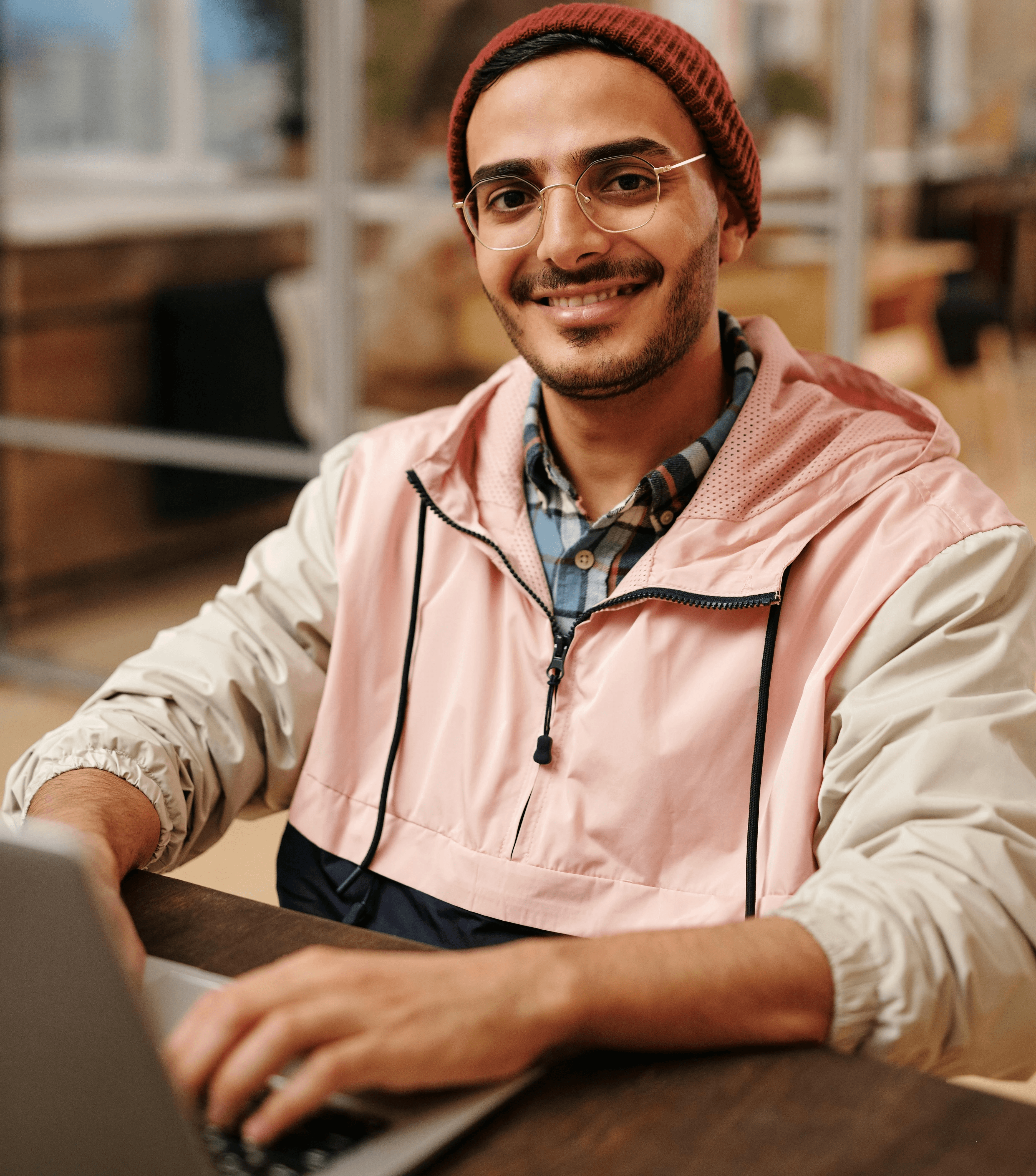 A man sitting in an office space in front of a laptop, smiling