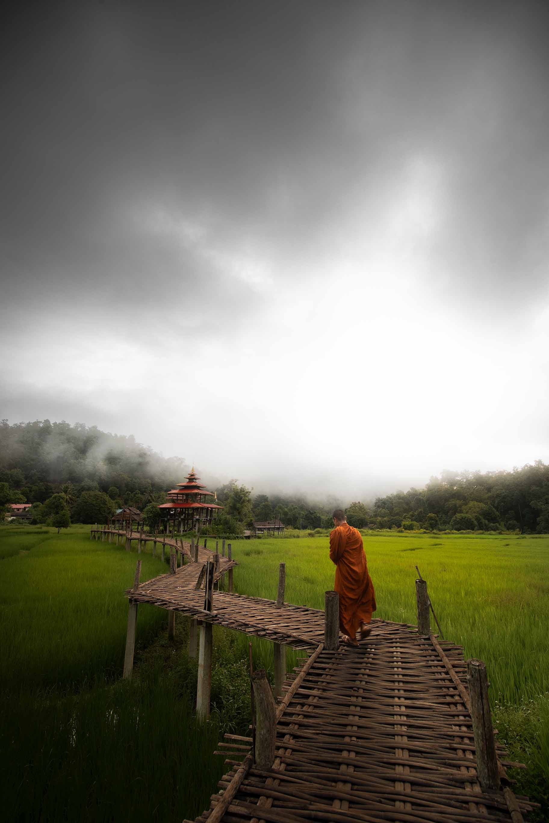 Bamboo bridge in Chiang Mai, Thailand with a monk walking on it.