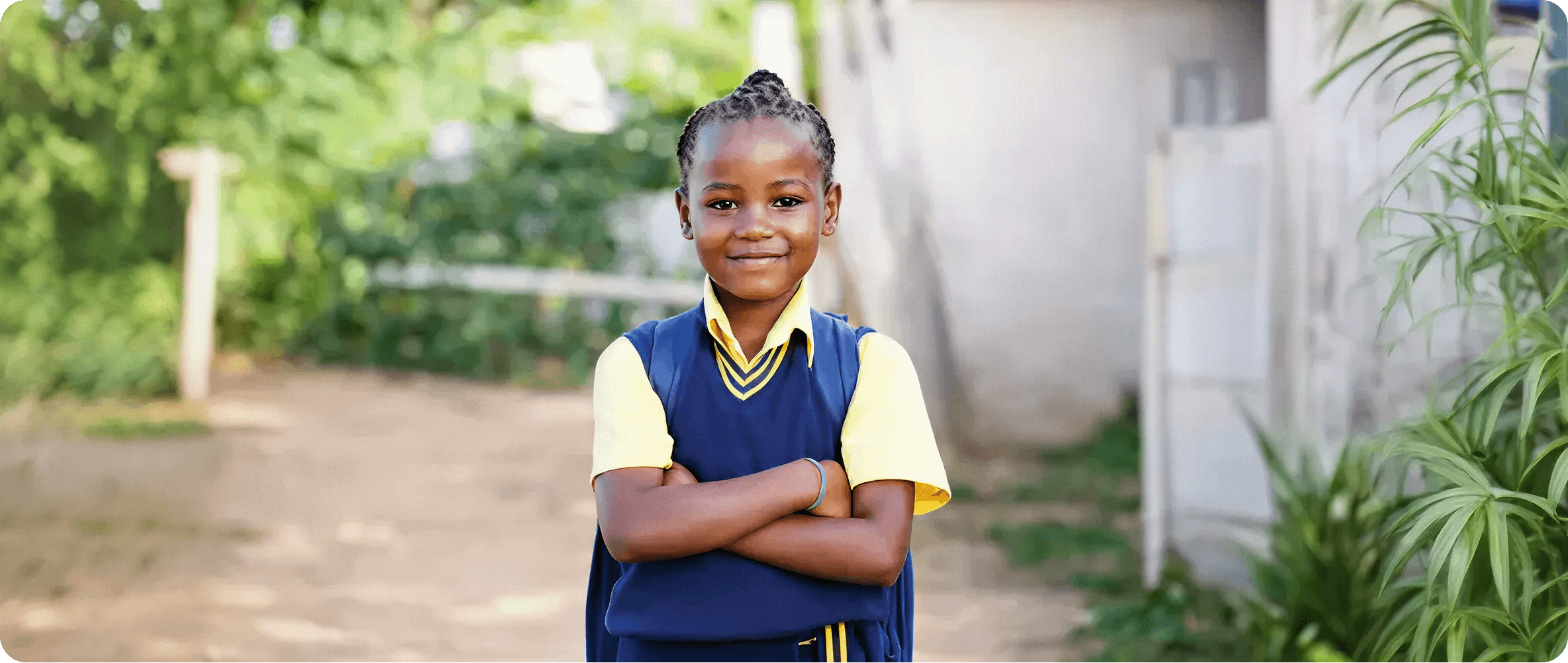Jeune fille souriante en uniforme scolaire bleue et jaune, les bras croisés, prête pour l'école.