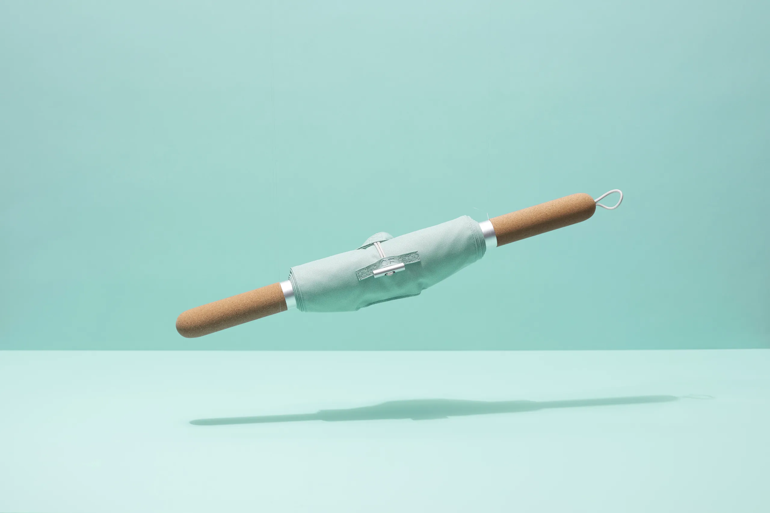 CastleFlexx strength and mobility device with mint fabric strap and cork handles on a light blue background