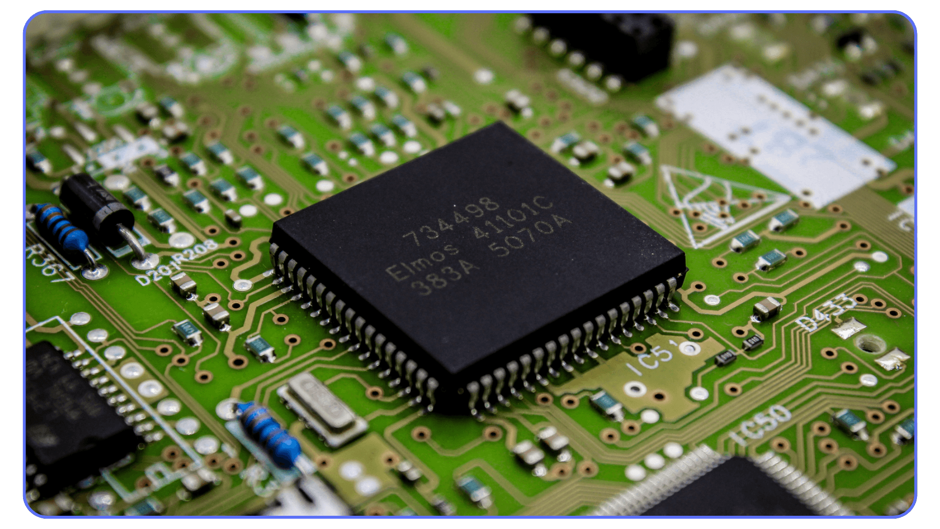 Computer processor on green circuit board – macro photo of a black microchip mounted on a printed circuit board with resistors and capacitors visible.