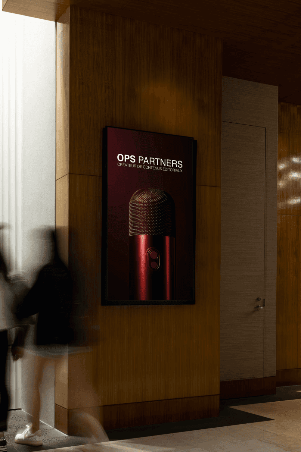 A man in a grey shirt sits in a dim office, gazing seriously at a computer screen. Blinds and office supplies create a focused and professional atmosphere.