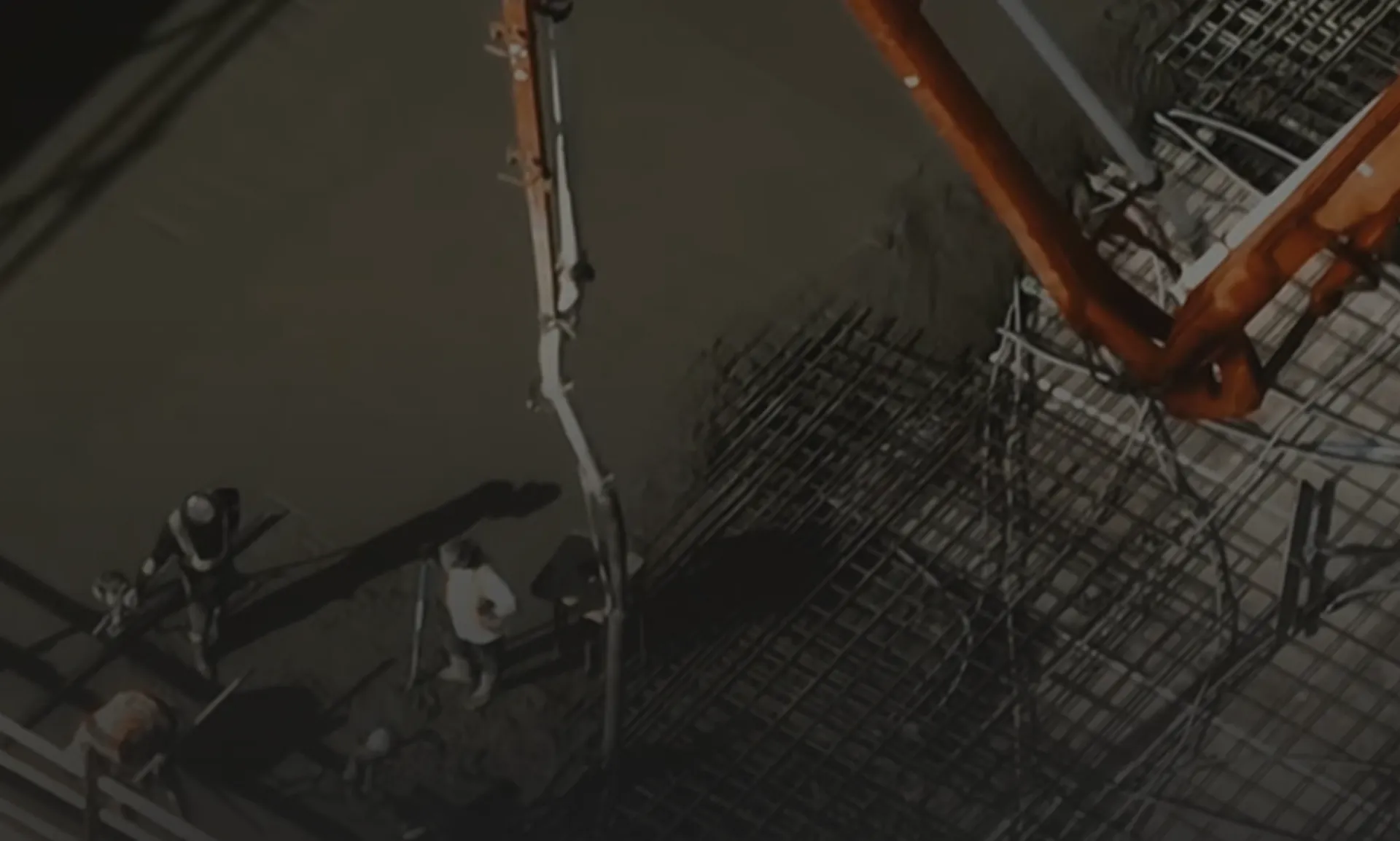 Modern architectural workspace with large floor-to-ceiling windows, surrounded by trees, and desks filled with design materials and books. Two blurred figures are walking through the space.