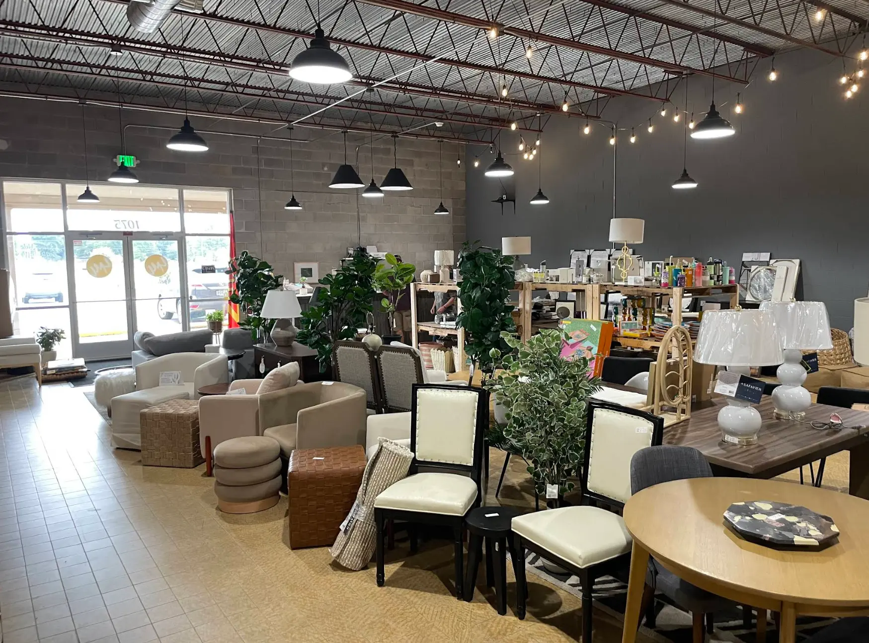 Bright furniture showroom with sofas, plants, and home decor displays near large front windows.