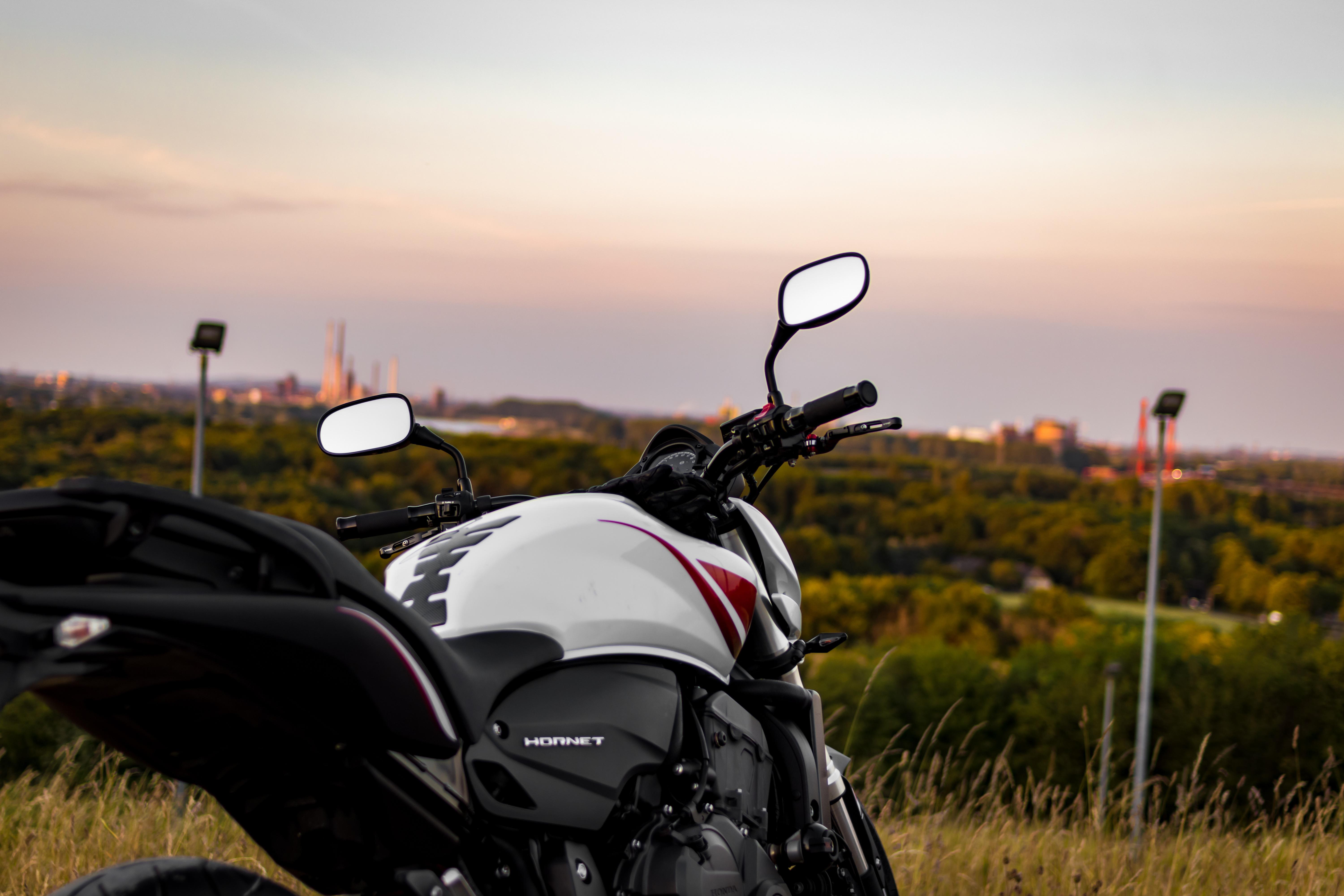 A winding road cuts through rocky terrain, surrounded by patches of green grass and illuminated by sunlight.