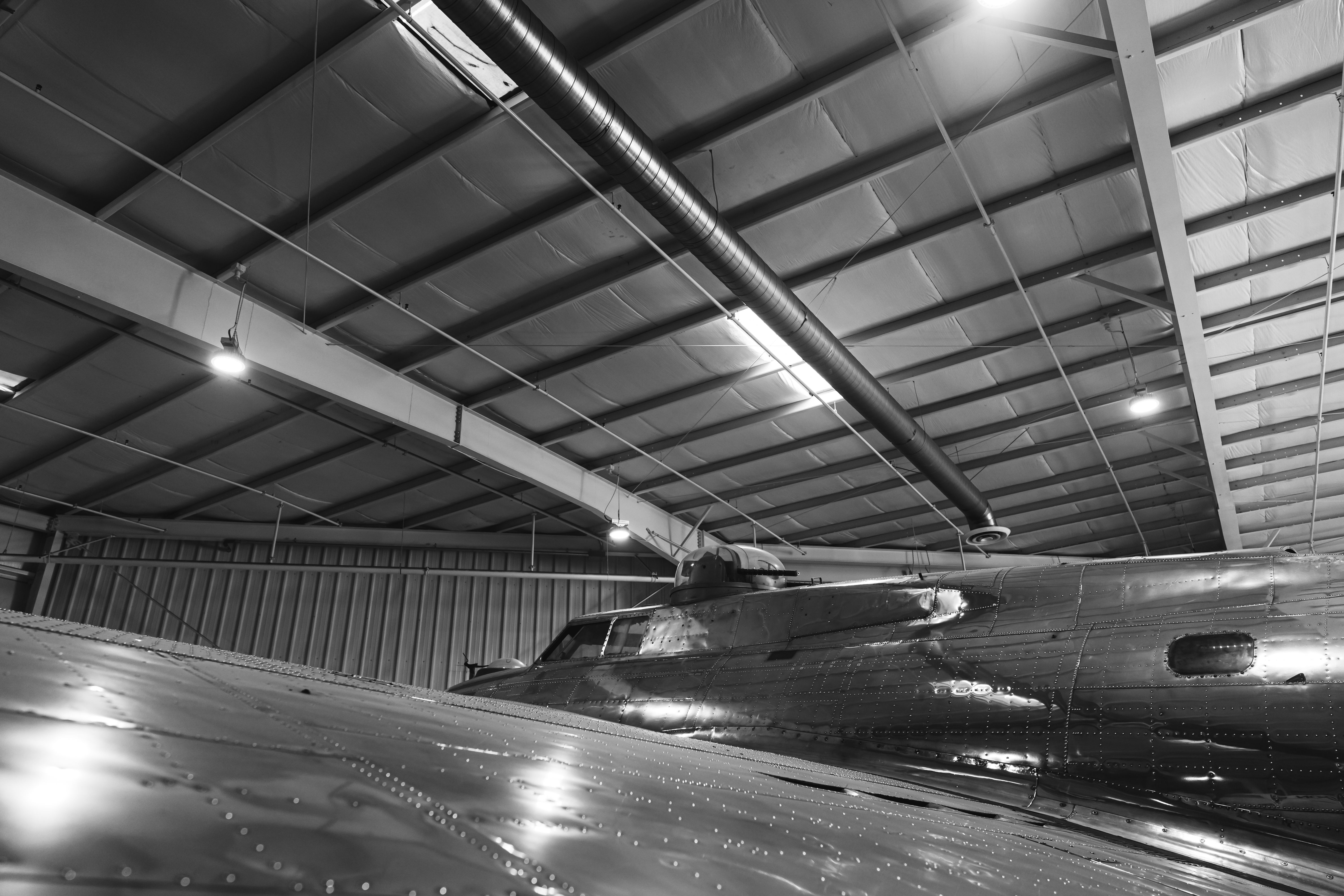 black-and-white-photo-of-an-airplane-parked-inside-a-large-hangar-with-industria - ricky-esquivel (pexels)
