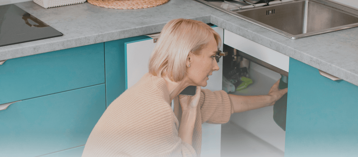 A woman checking a water leak in the kitchen