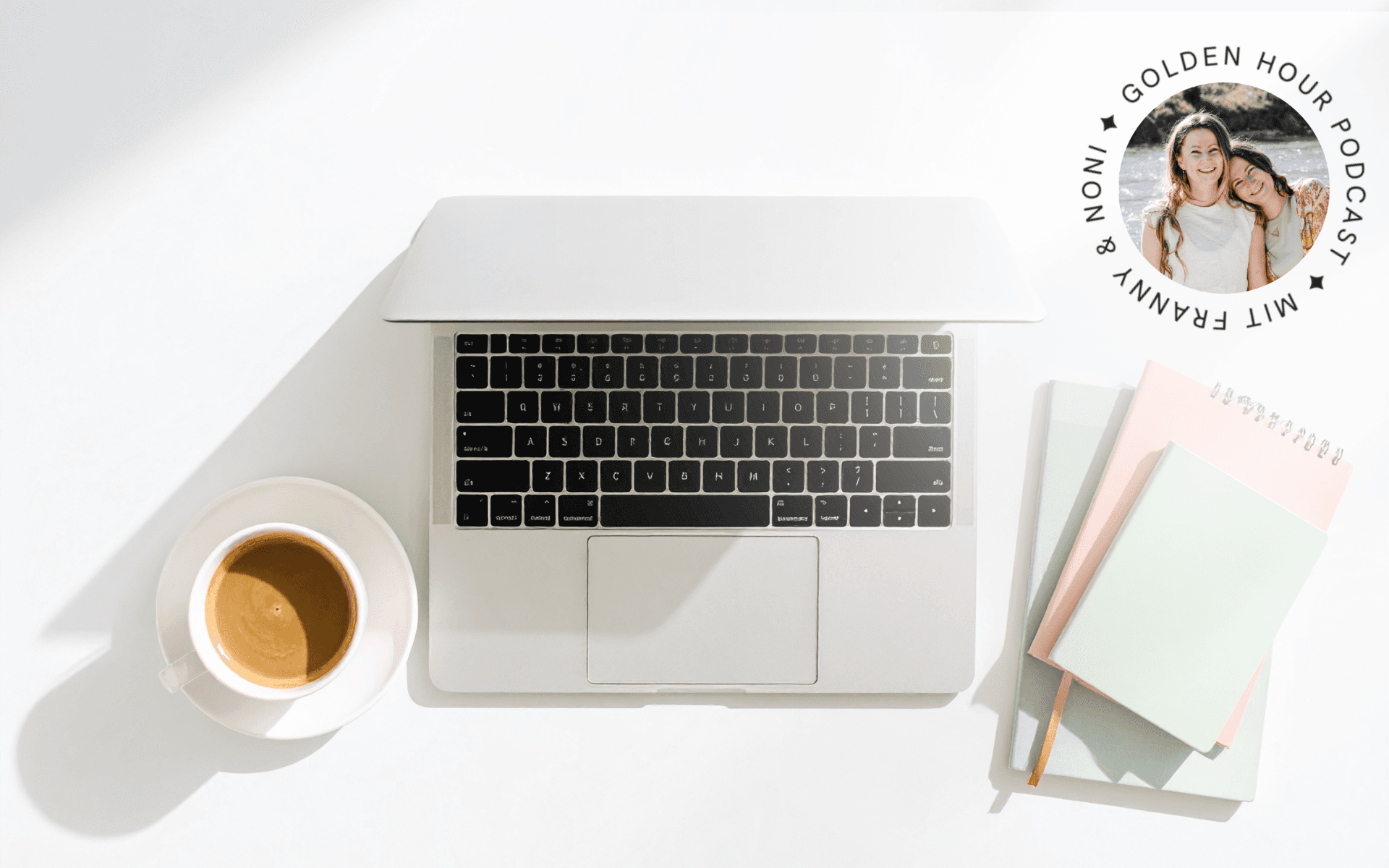 cup of coffee next to a laptop next to some journals and a pen on a desk