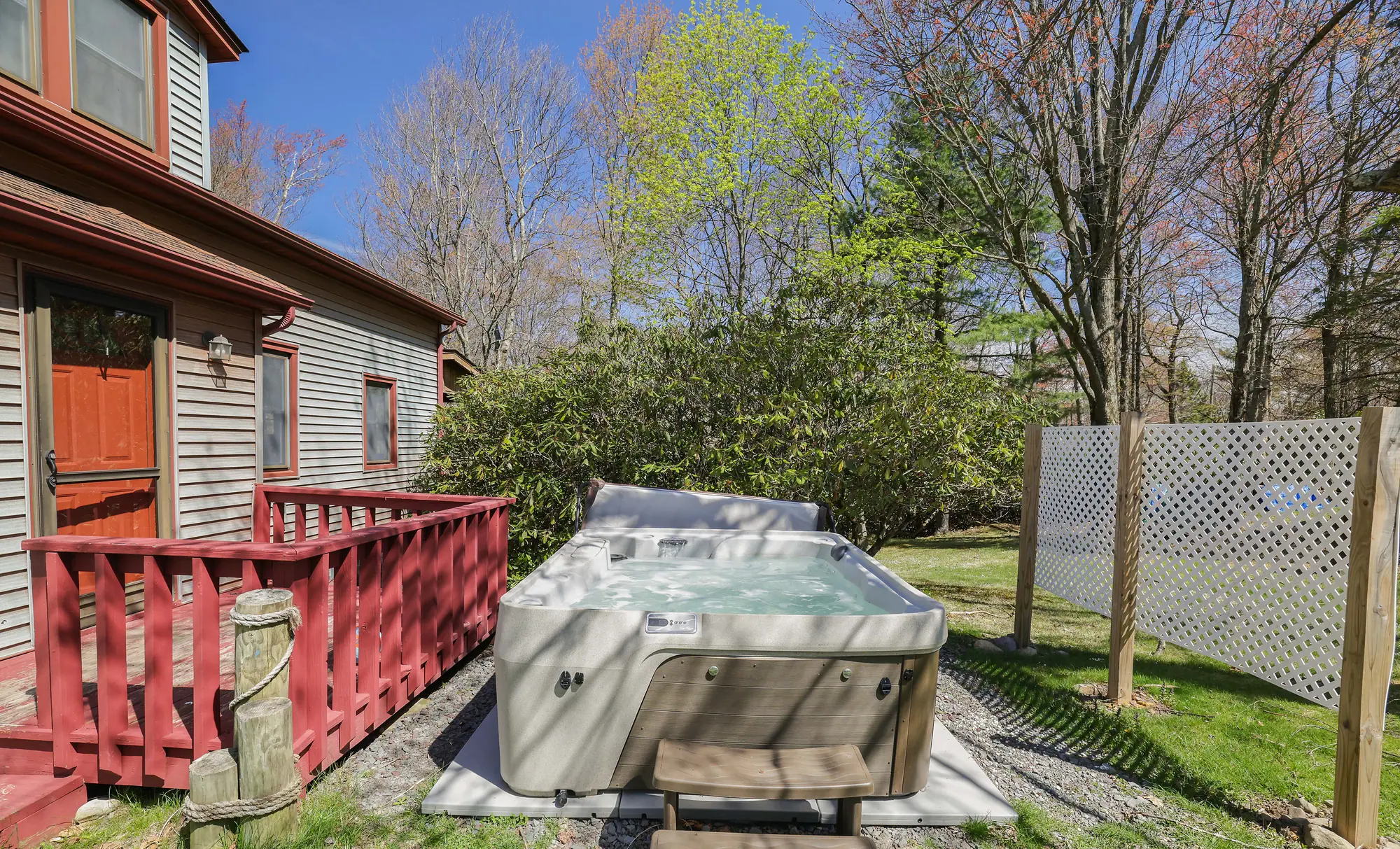 Private hot tub beside the red deck with lattice privacy screen at DeerPath Crossing, Lake Harmony, PA