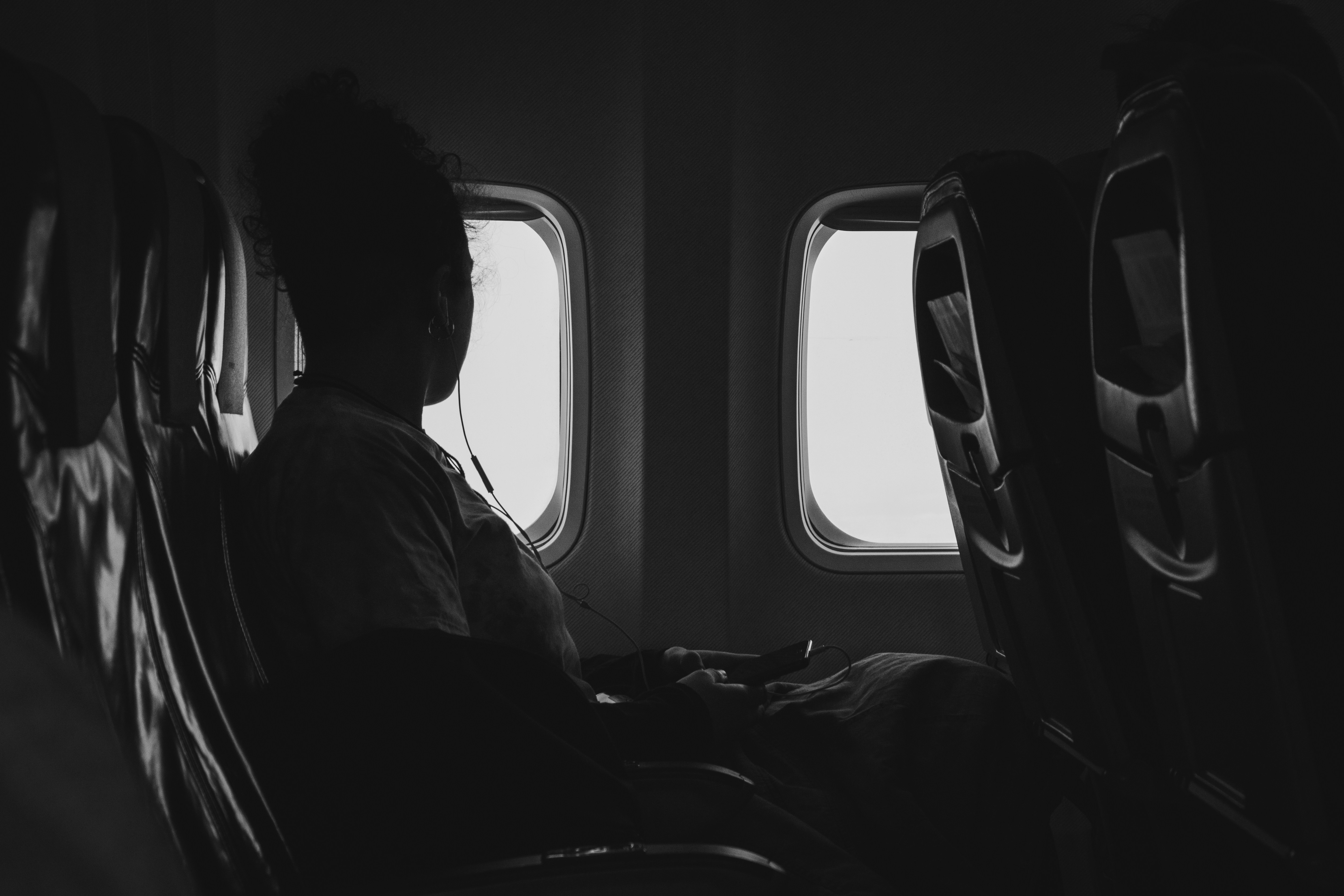 grayscale photography of person riding air plane while watching window